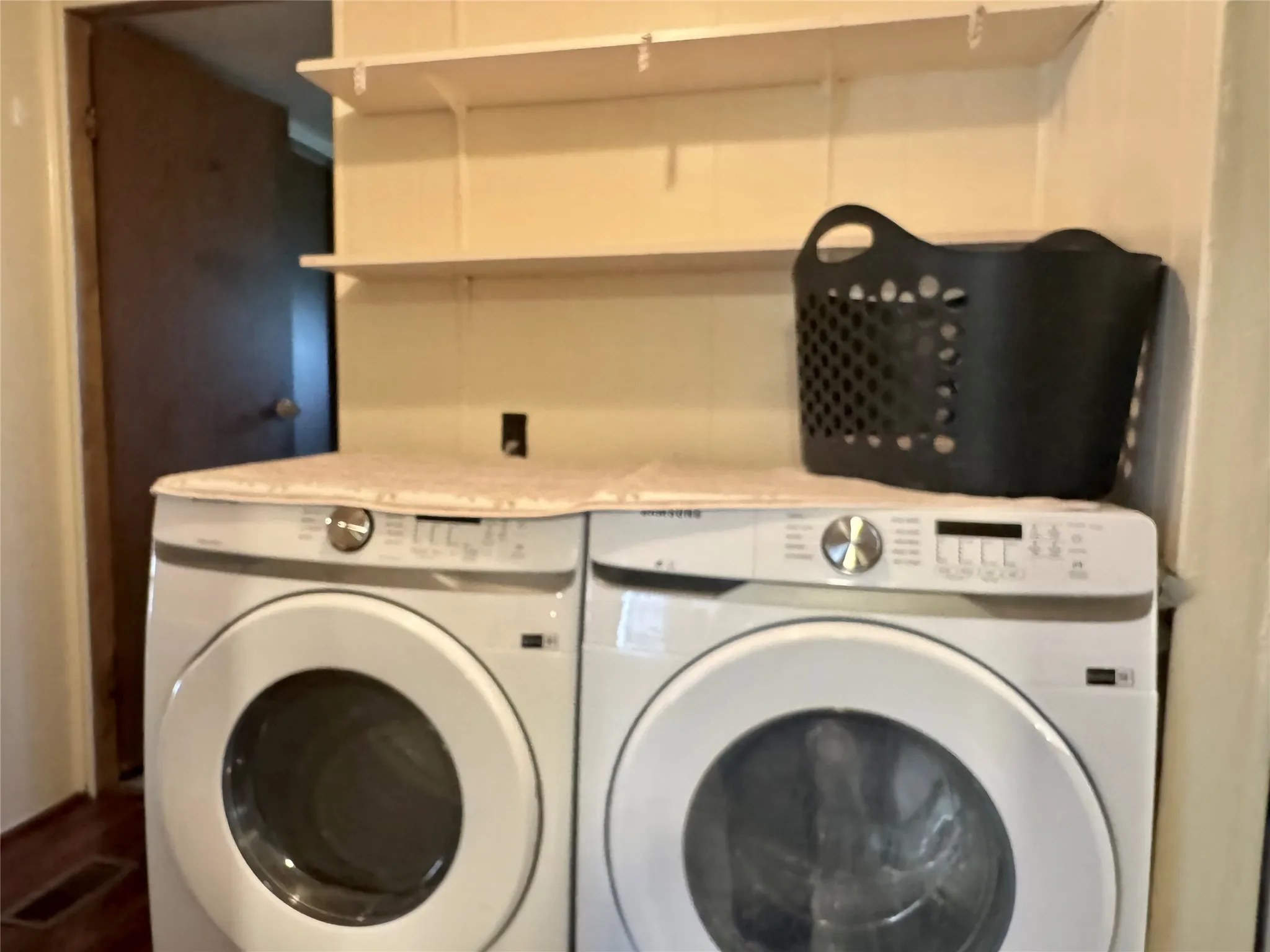 Laundry room with built-in shelving above washer/dryer area. Note: Washer and dryer do not convey.