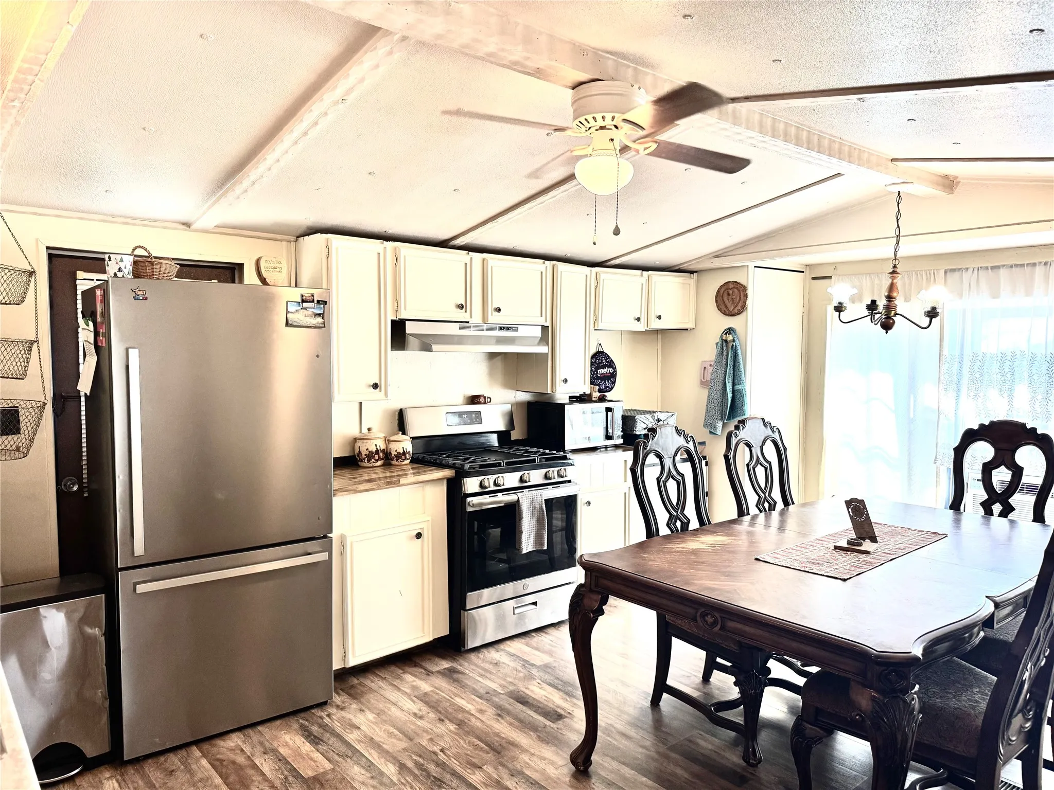 Kitchen featuring white cabinetry, stainless steel appliances, laminate wood-finish flooring, and a ceiling fan. Fridge does NOT convey.