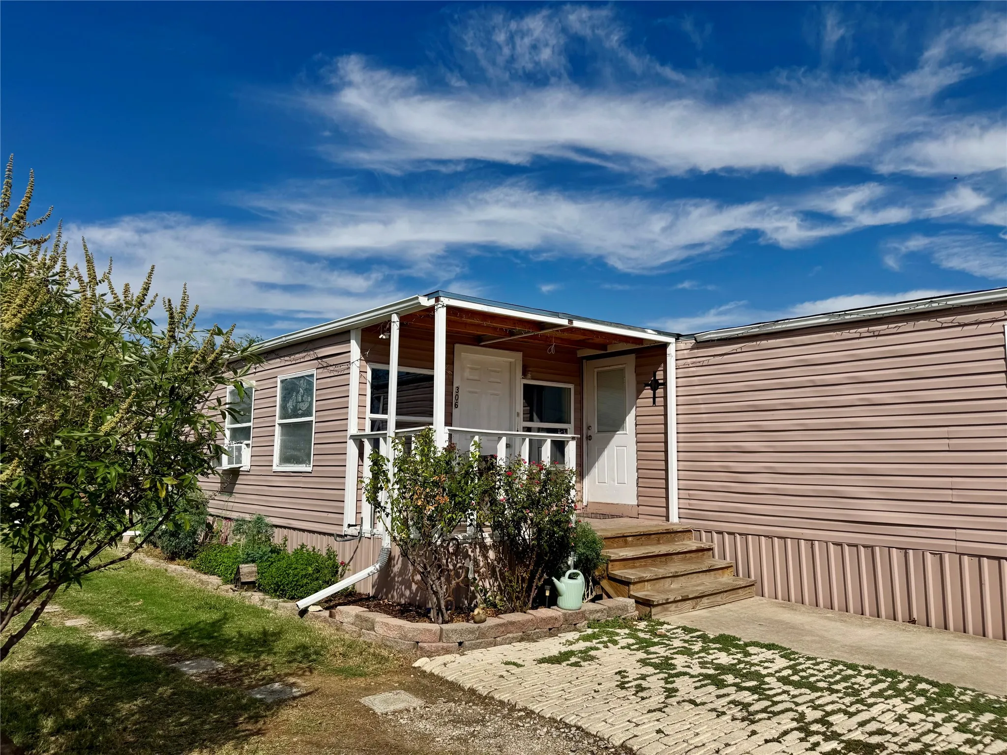 Front exterior featuring a covered porch with white railings, and a small landing with wooden steps