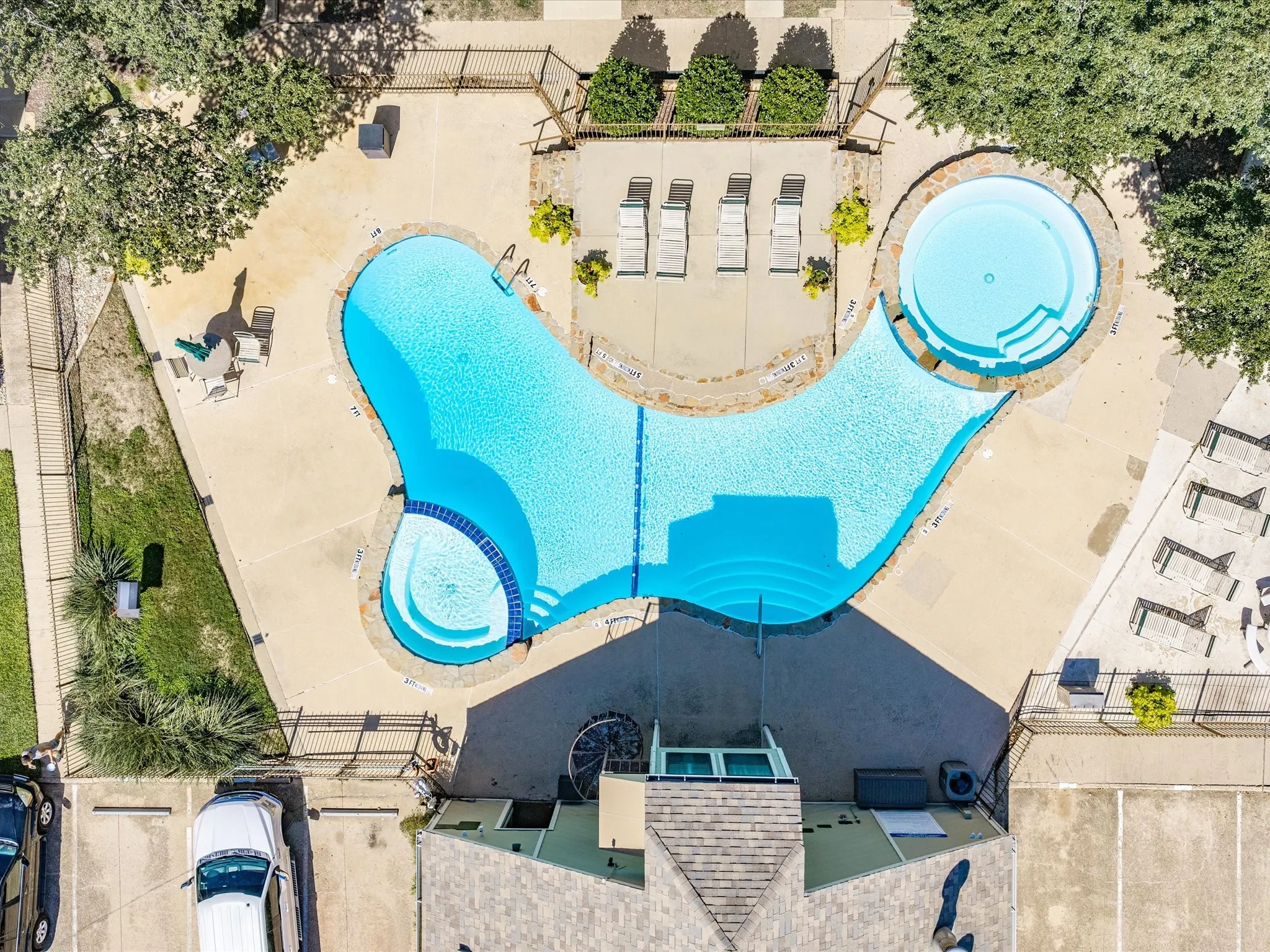 Resort-style pool with integrated spa, expansive concrete decking, and designated lounging areas