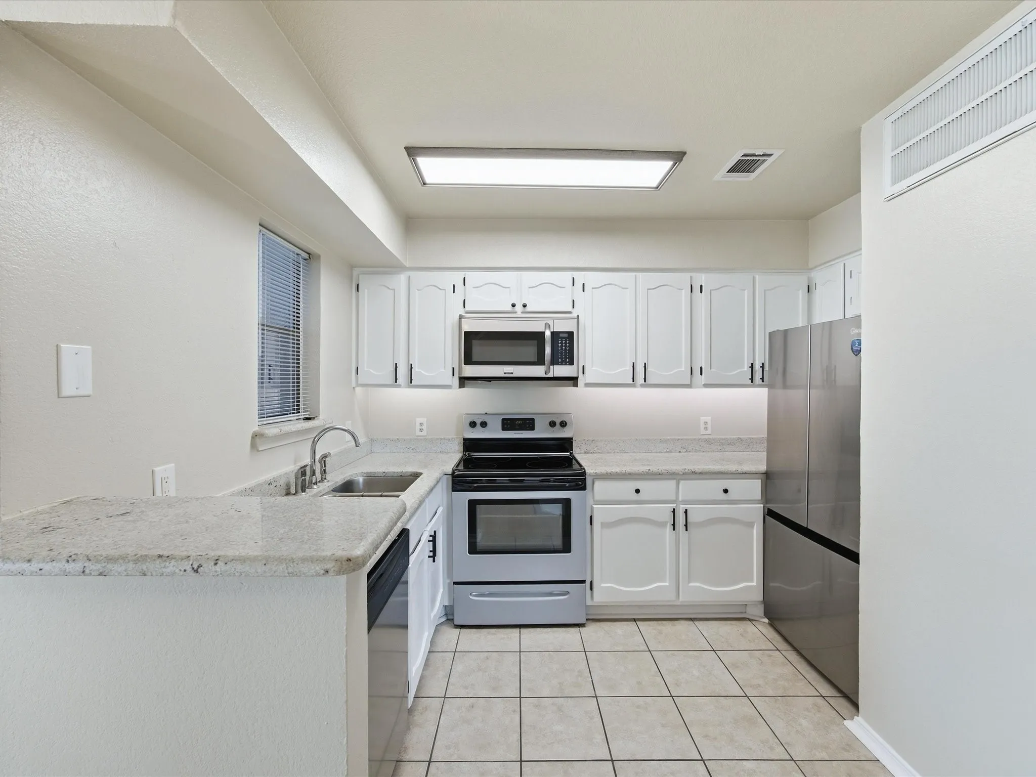 Kitchen featuring white cabinetry, stainless steel appliances, a stainless steel sink, and light-toned countertops