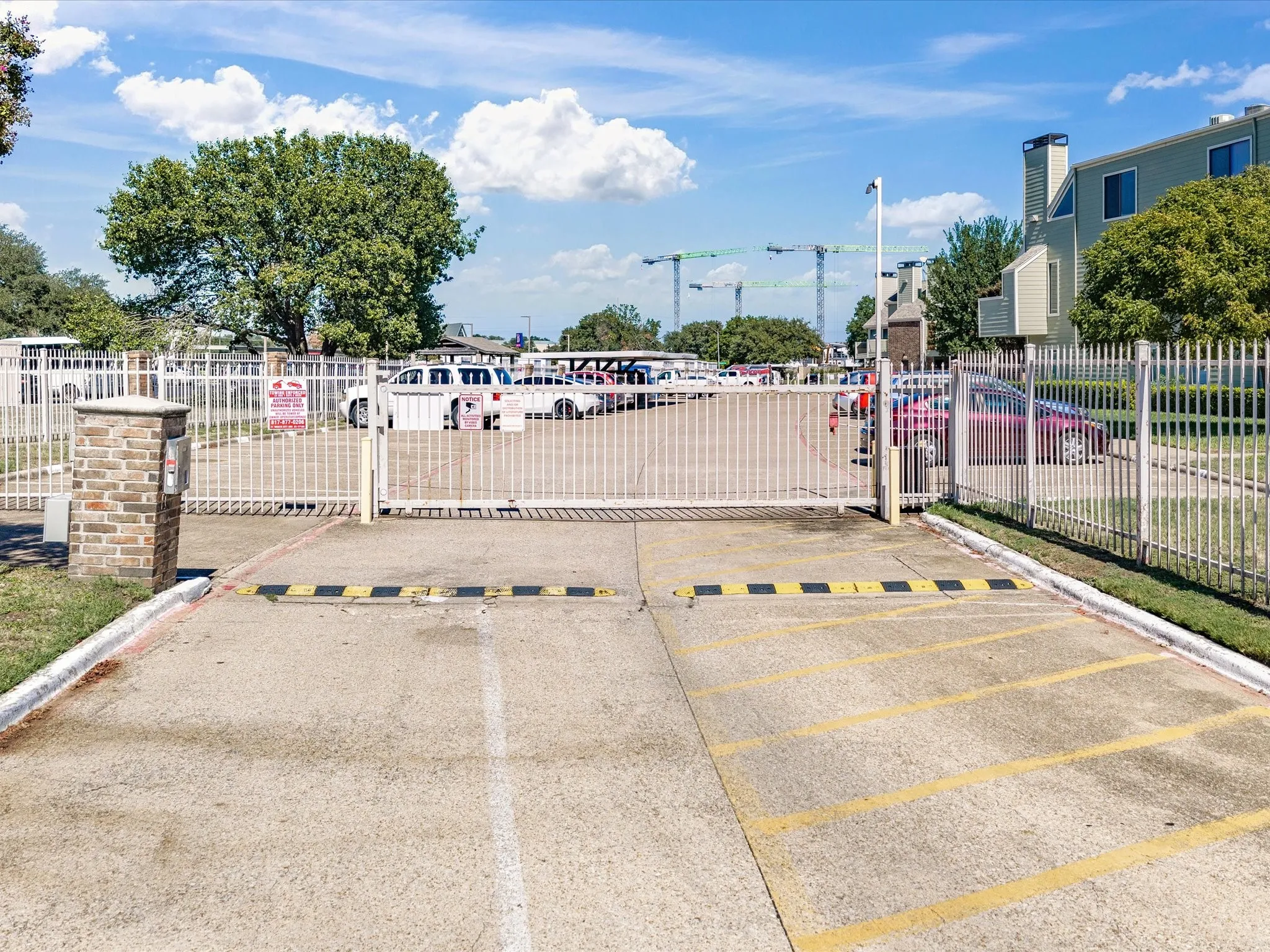 Gated entry with a brick-clad pillar and white metal fencing