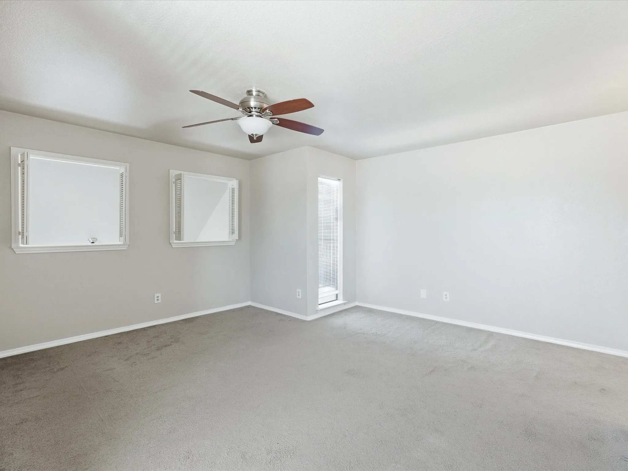 Ceiling fan with light fixture, neutral carpet flooring, and multiple windows
