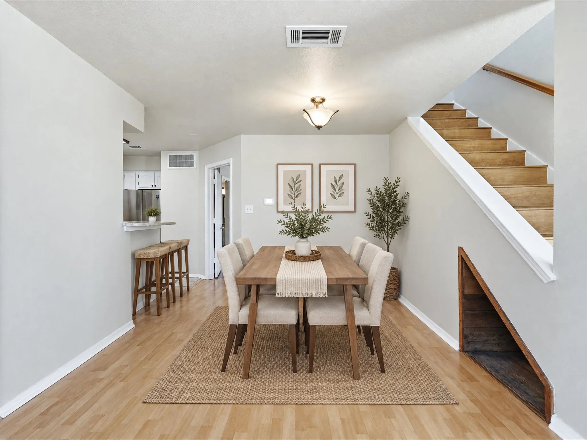 Dining area with wood-finish flooring, staircase with wood treads, and an under-stair storage nook