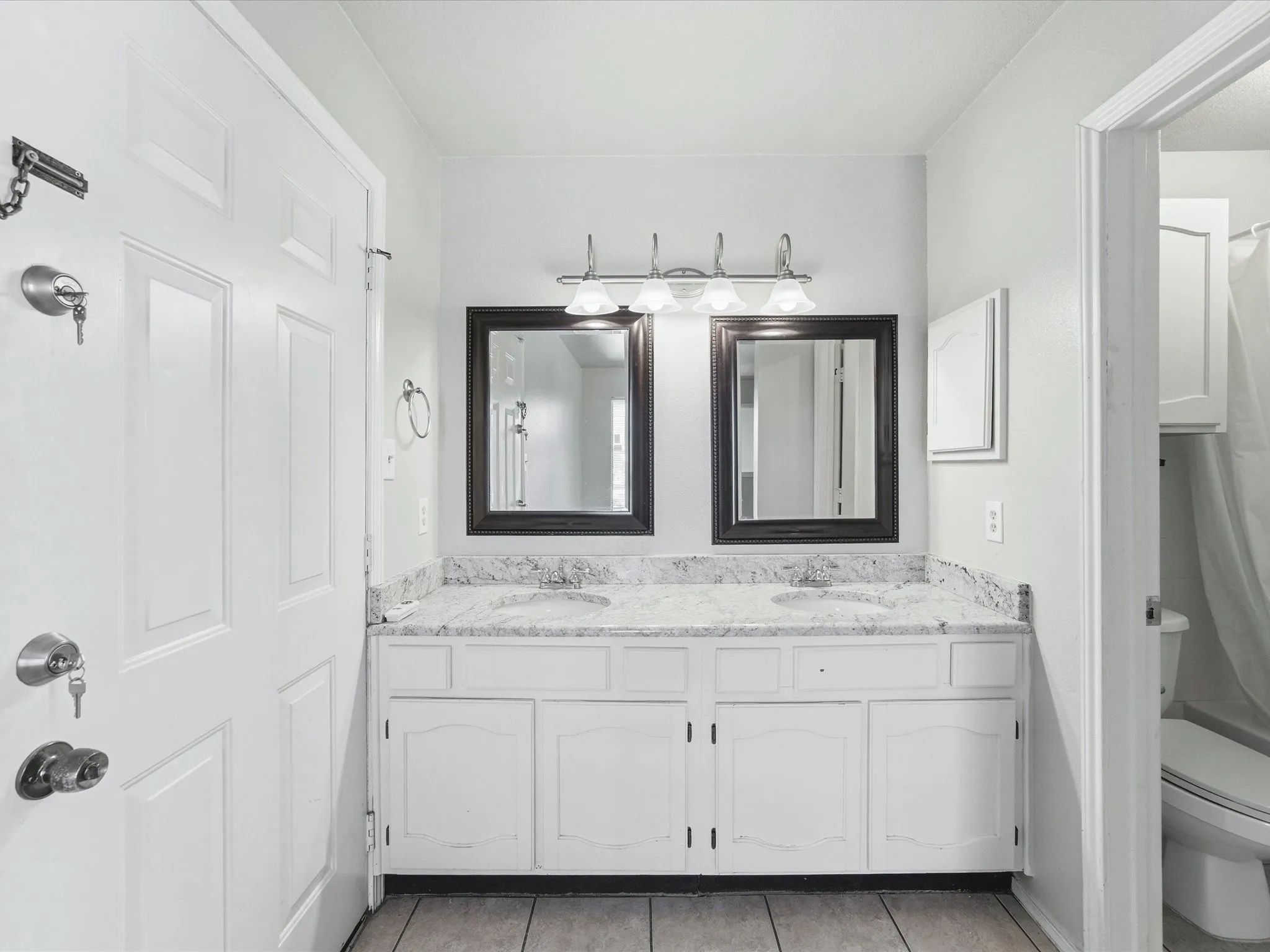 Double vanity with undermount sinks, stone countertops, framed mirrors, and chrome light fixture