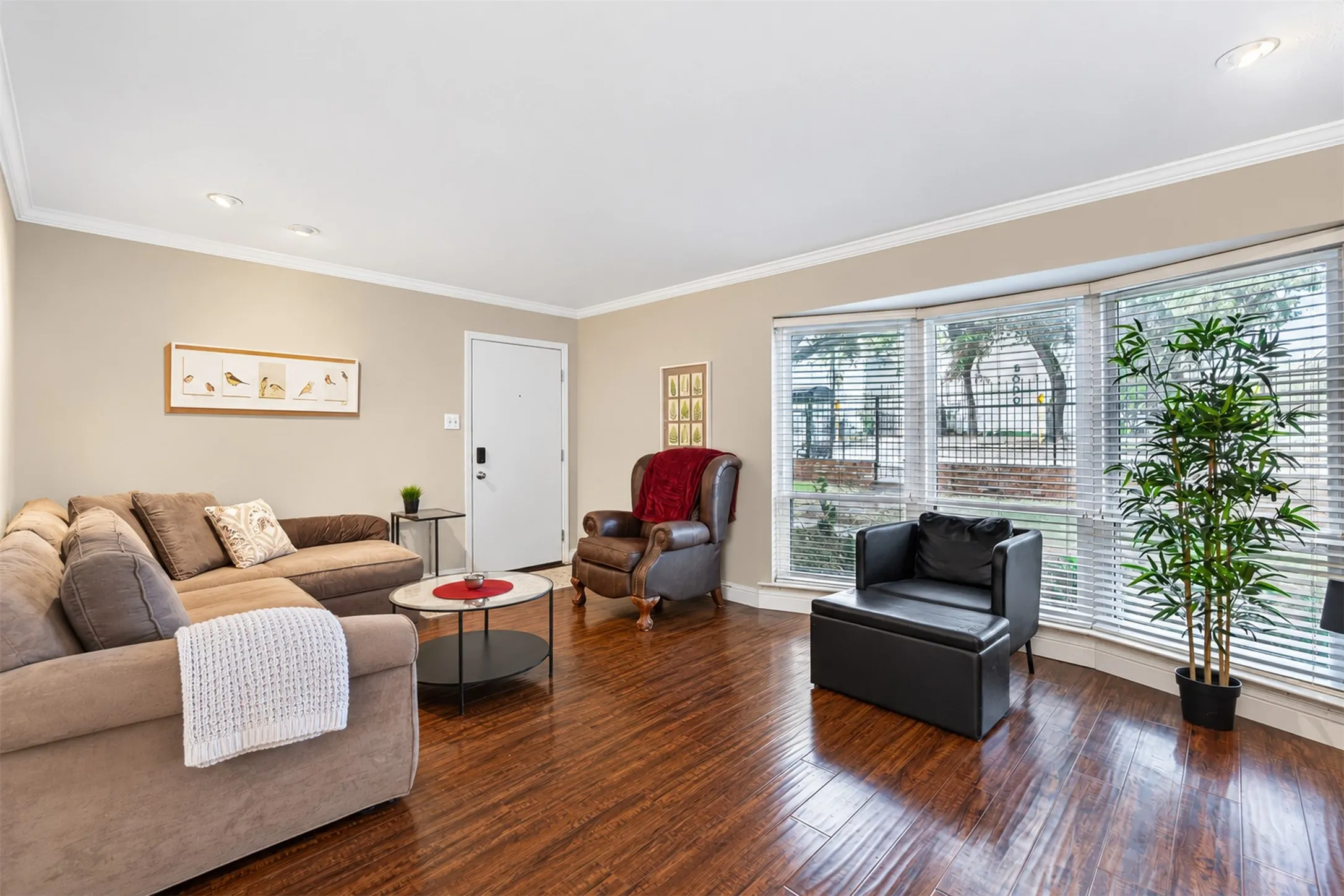 Wood-finish flooring, recessed lighting, crown molding, a bay window, and a white entry door