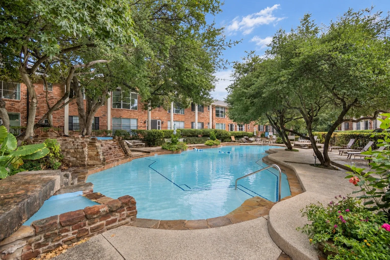 Outdoor swimming pool with integrated spa and rock waterfall feature