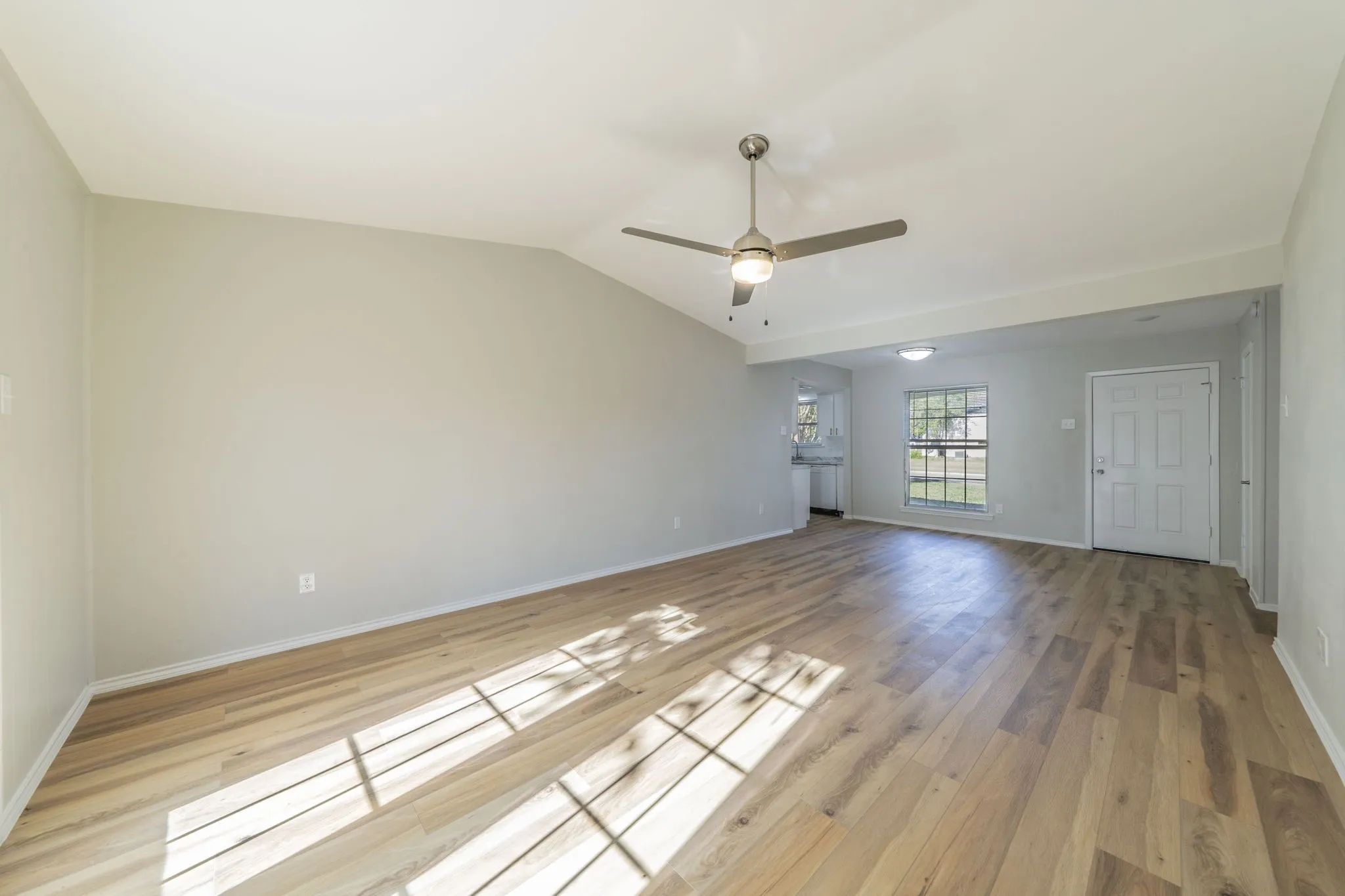Vaulted ceiling, wood-finish flooring, ceiling fan with integrated lighting, recessed lighting, and a paneled entry door