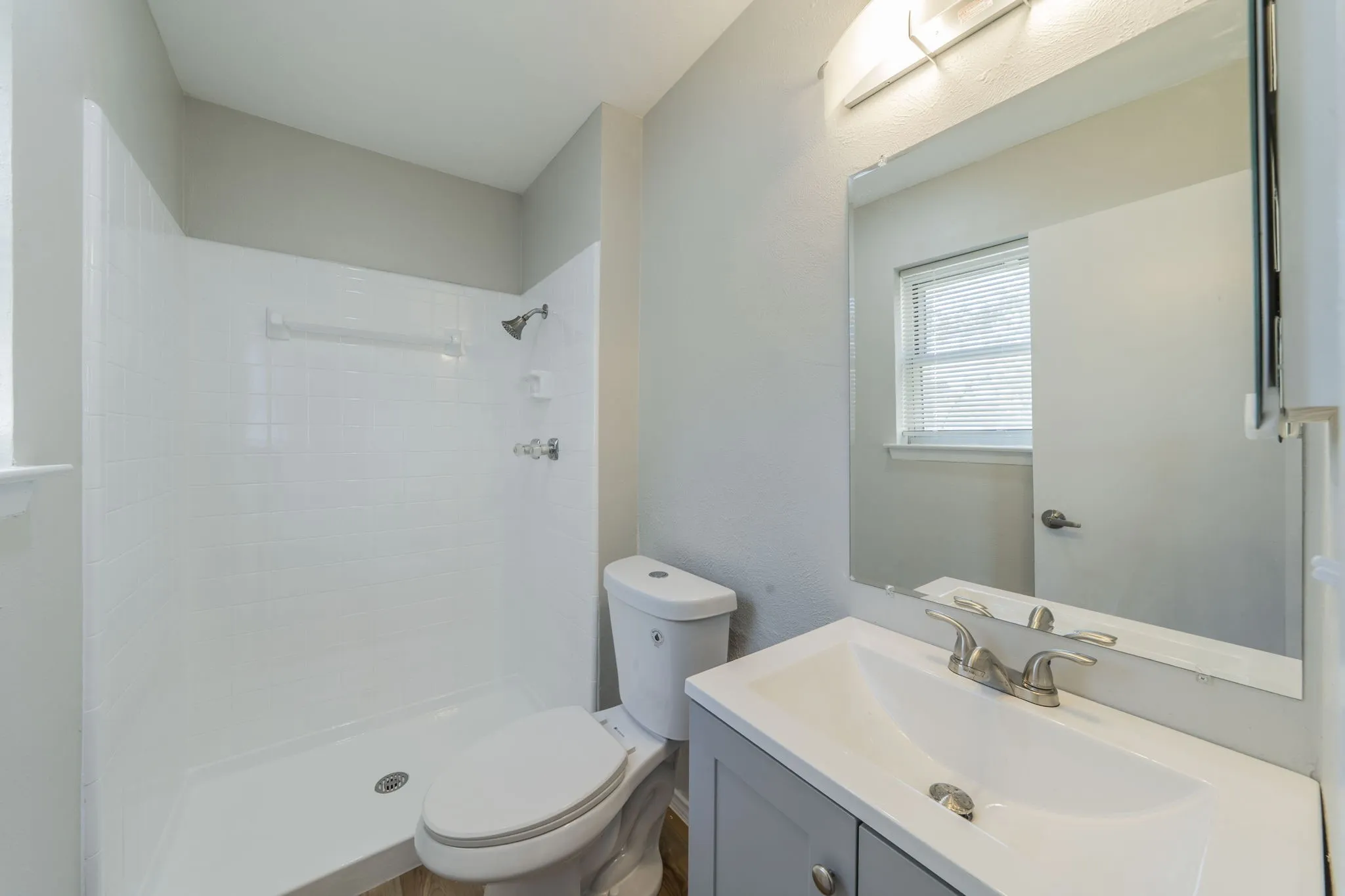 Modern bathroom featuring a single vanity with a gray cabinet, an integrated sink, and brushed nickel fixtures