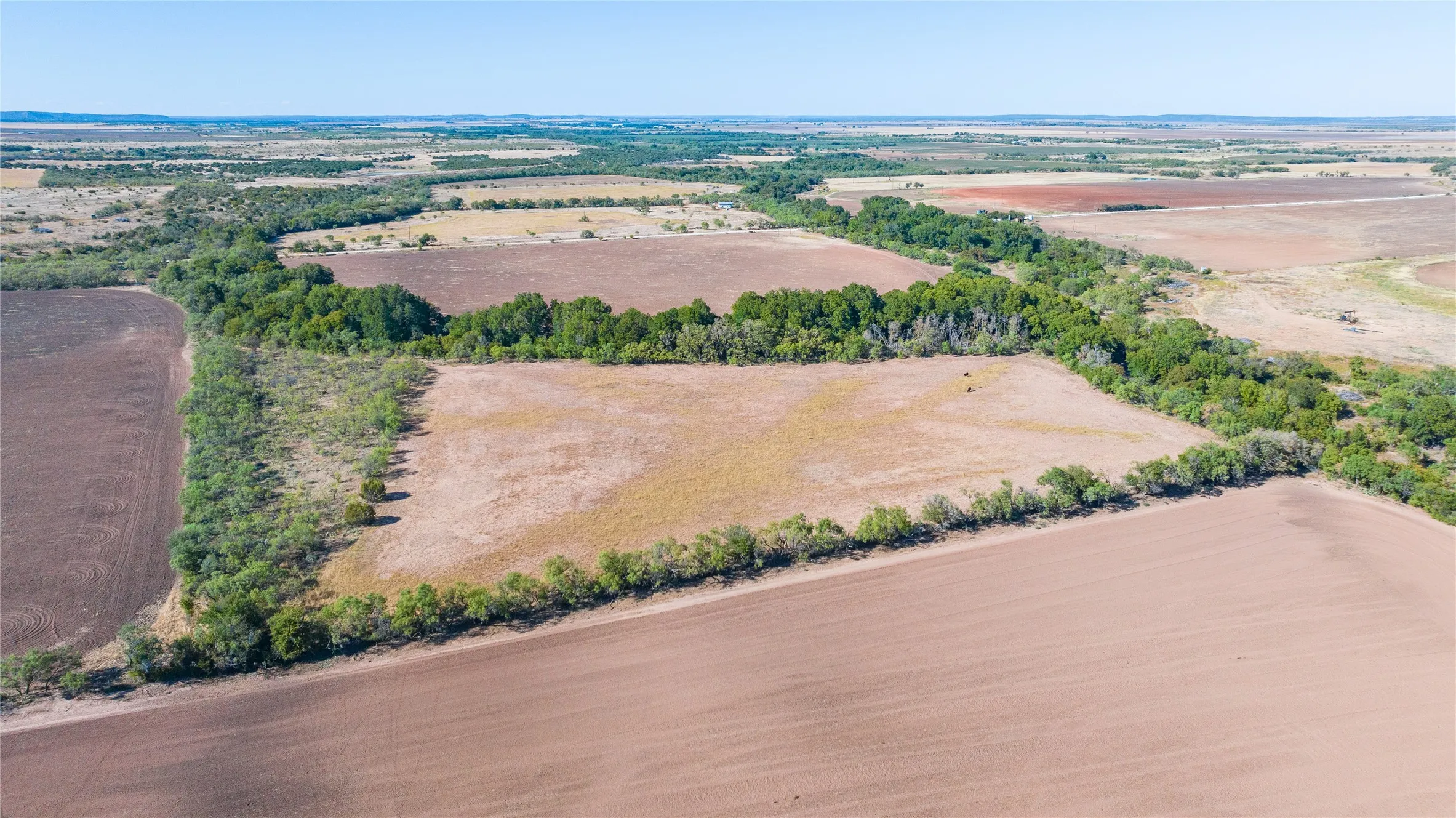 Expansive agricultural land featuring cultivated fields and natural tree lines