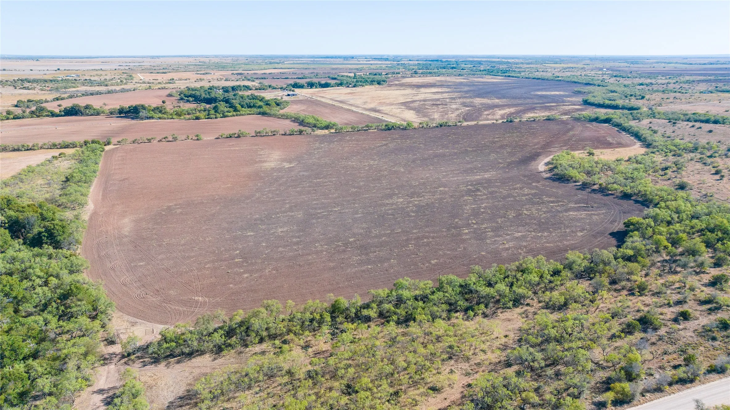 Expansive tilled agricultural land, surrounded by natural vegetation
