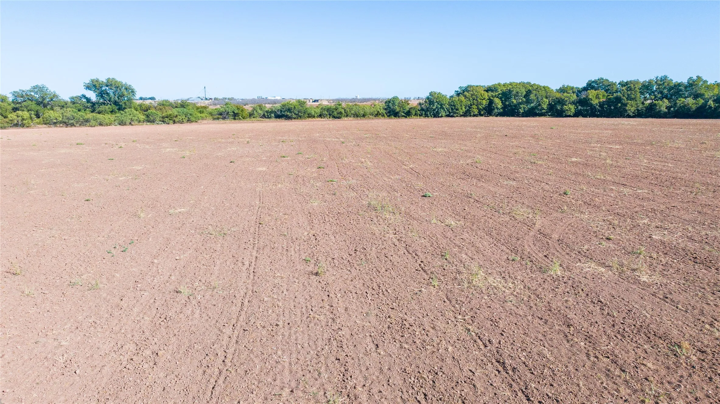 Expansive land parcel featuring cleared ground and mature tree line