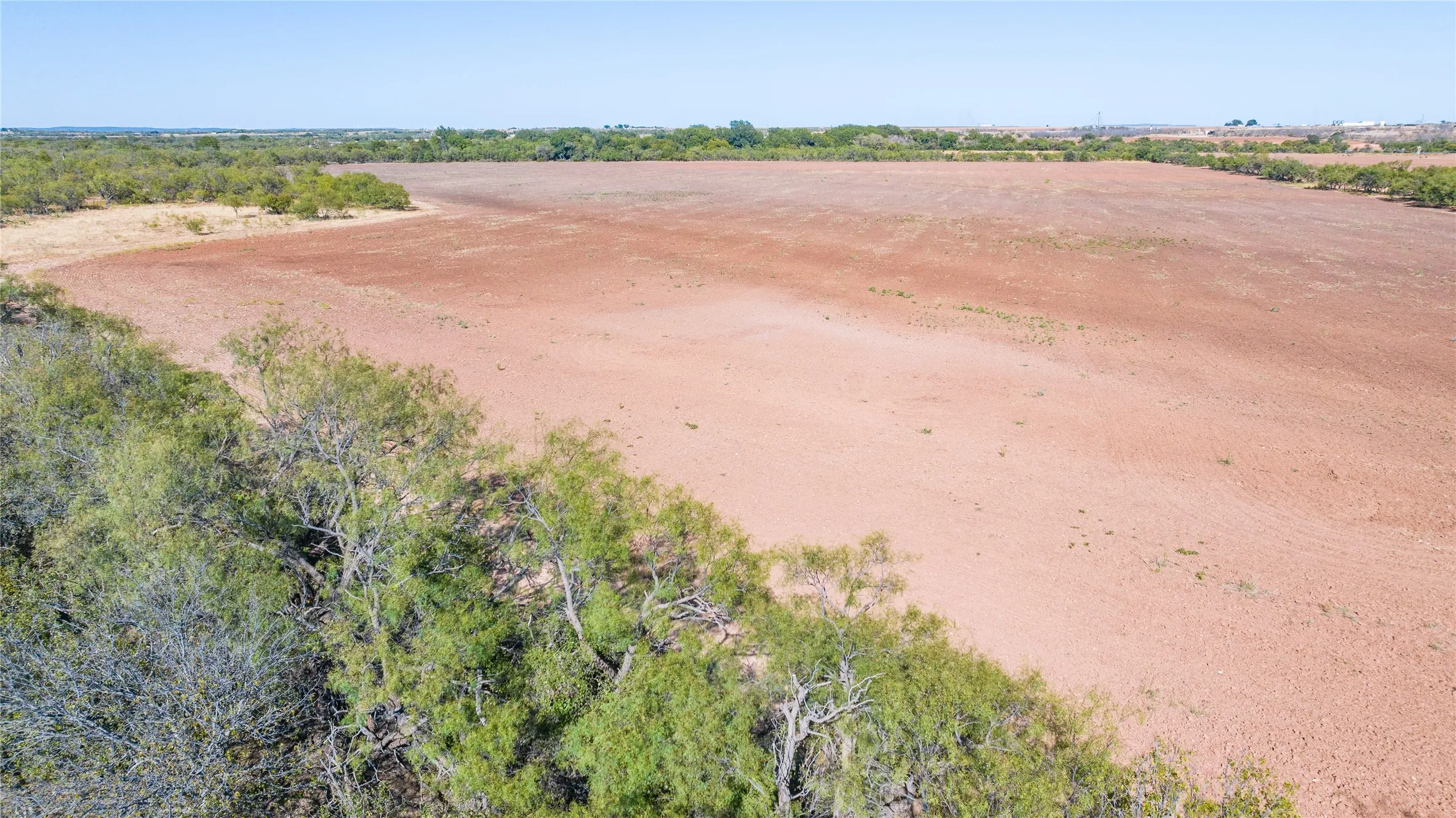 Expansive undeveloped land featuring a cleared, level terrain bordered by natural vegetation