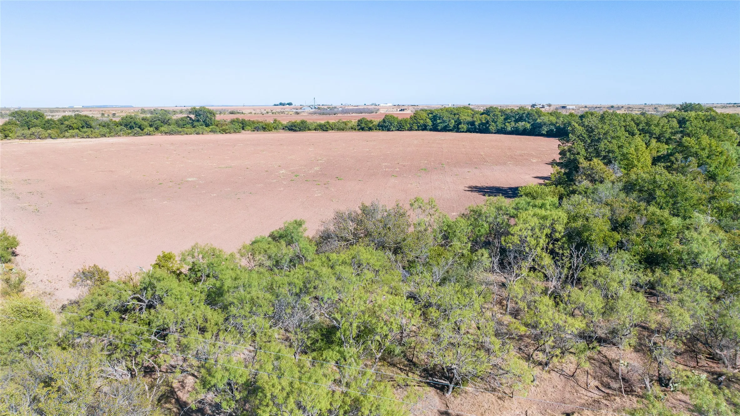 Expansive land parcel featuring a cleared field and mature perimeter trees