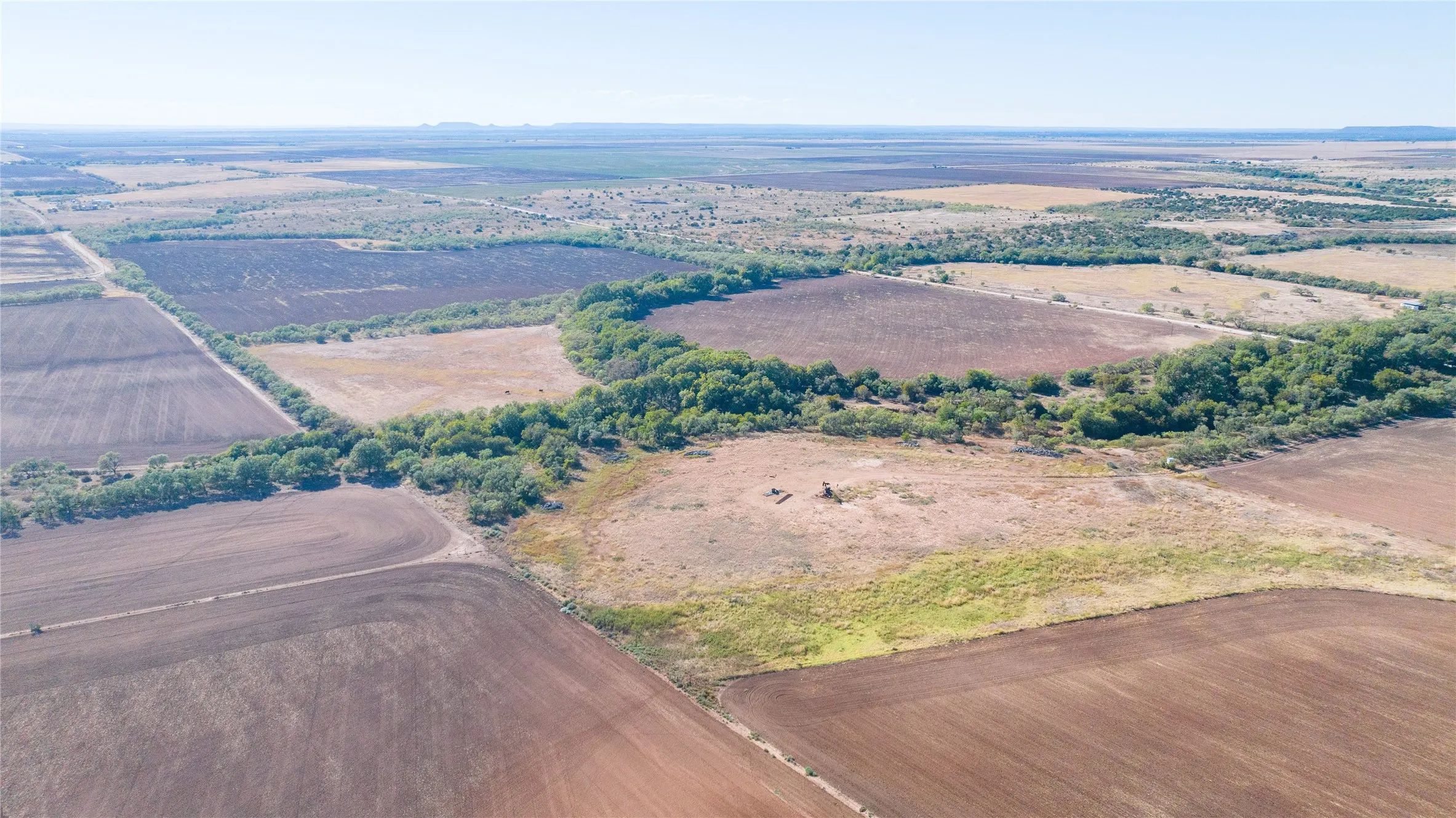 Expansive agricultural acreage featuring cultivated fields, natural tree lines, and open land