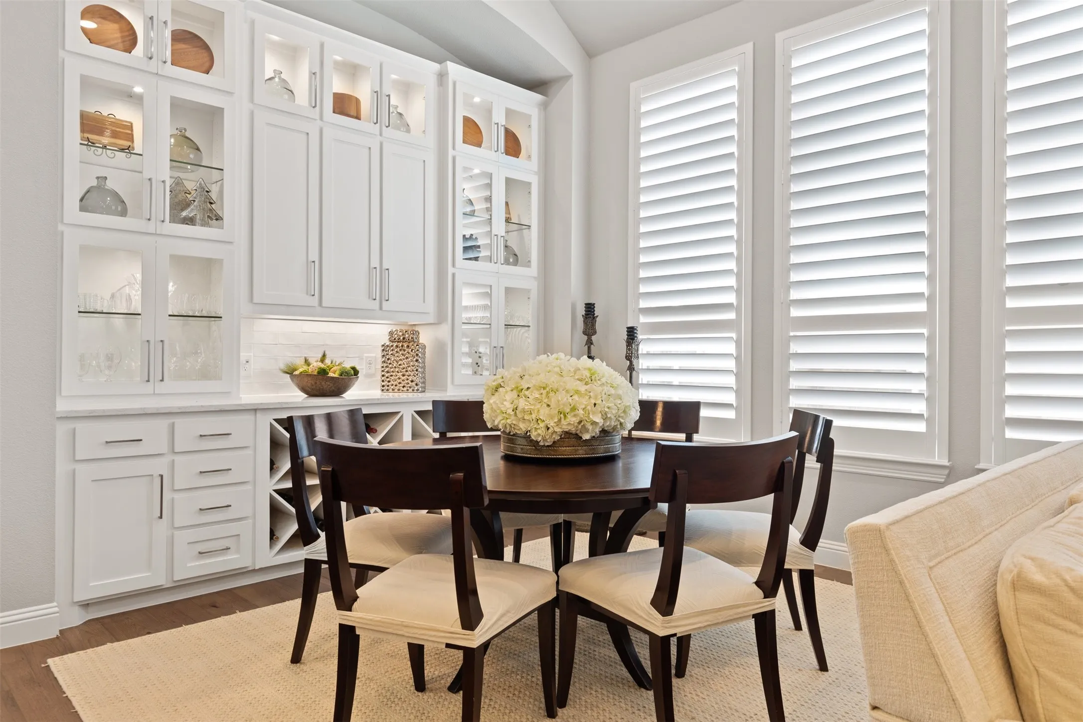 Dining room with built-in white cabinetry with glass display fronts, integrated wine storage.