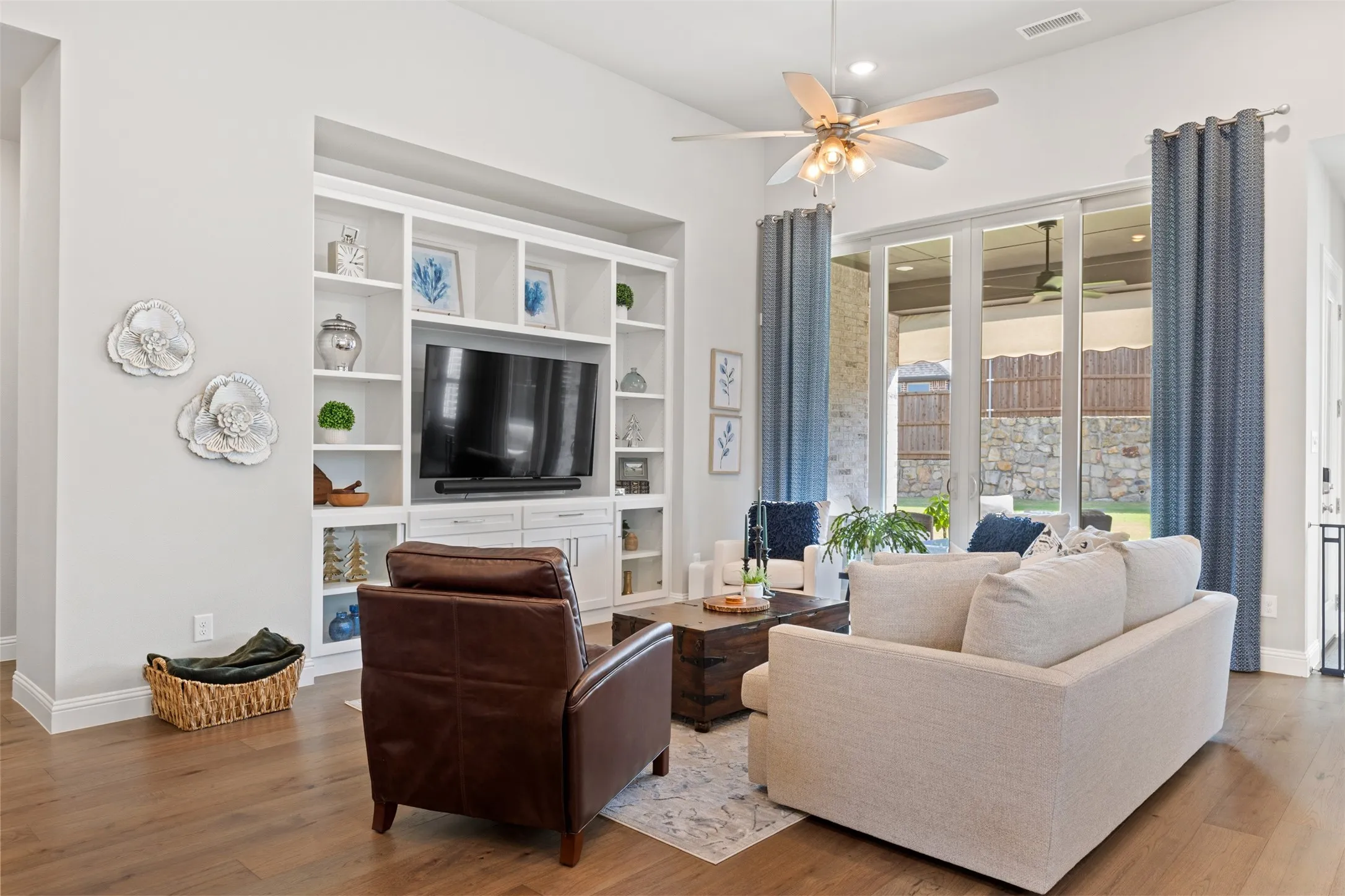 Living room with integrated built-in cabinetry, wood-finish flooring, recessed lighting, and large sliding glass doors