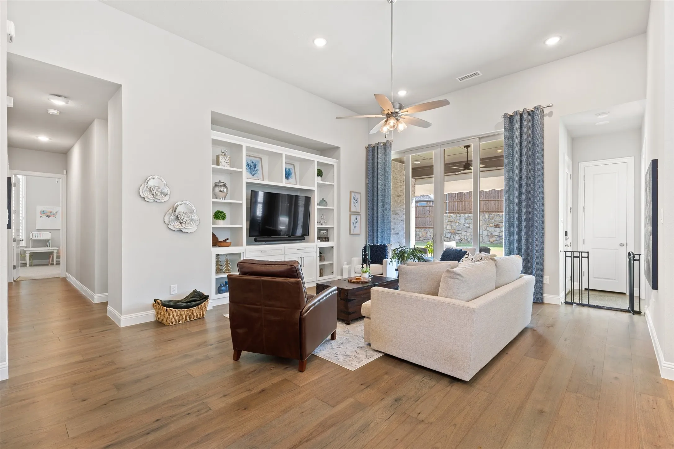 Living room with integrated built-in cabinetry, wood-finish flooring, recessed lighting, and large sliding glass doors