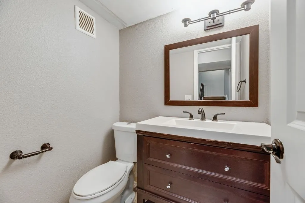 Rich wood-finish vanity with drawer storage, white integrated sink, and bronze-finish faucet
