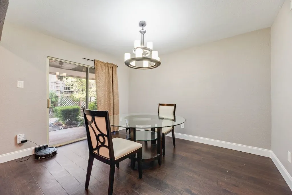 Wood-finish flooring, white baseboards, and a contemporary chandelier