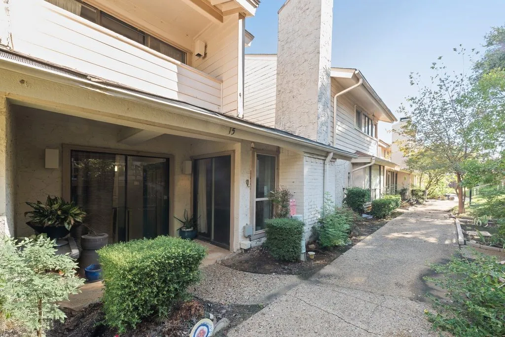 Exterior featuring a chimney, sliding glass doors, upper-level windows, and a concrete pathway