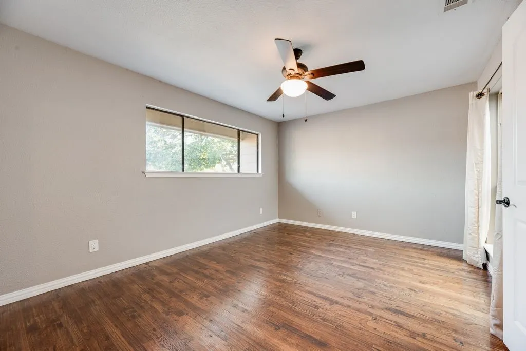 2nd Bedroom- Wood-finish flooring, neutral wall tones, multi-pane window, and a ceiling fan with integrated lighting