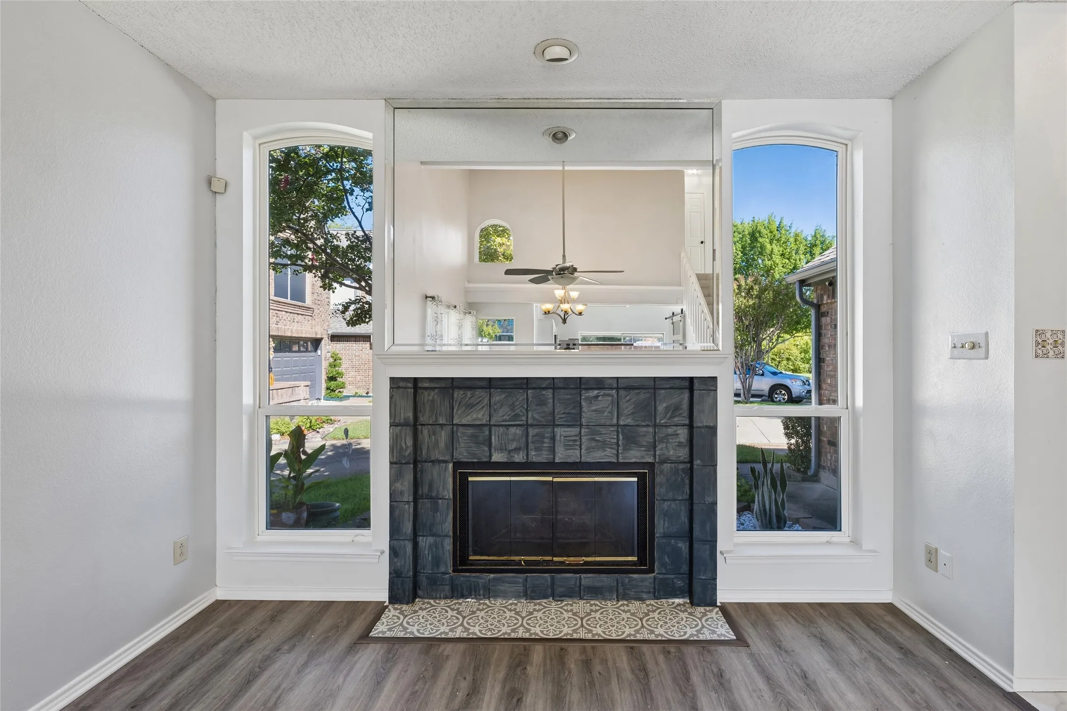 Fireplace enveloped by windows offering a view of the tranquil greenbelt.