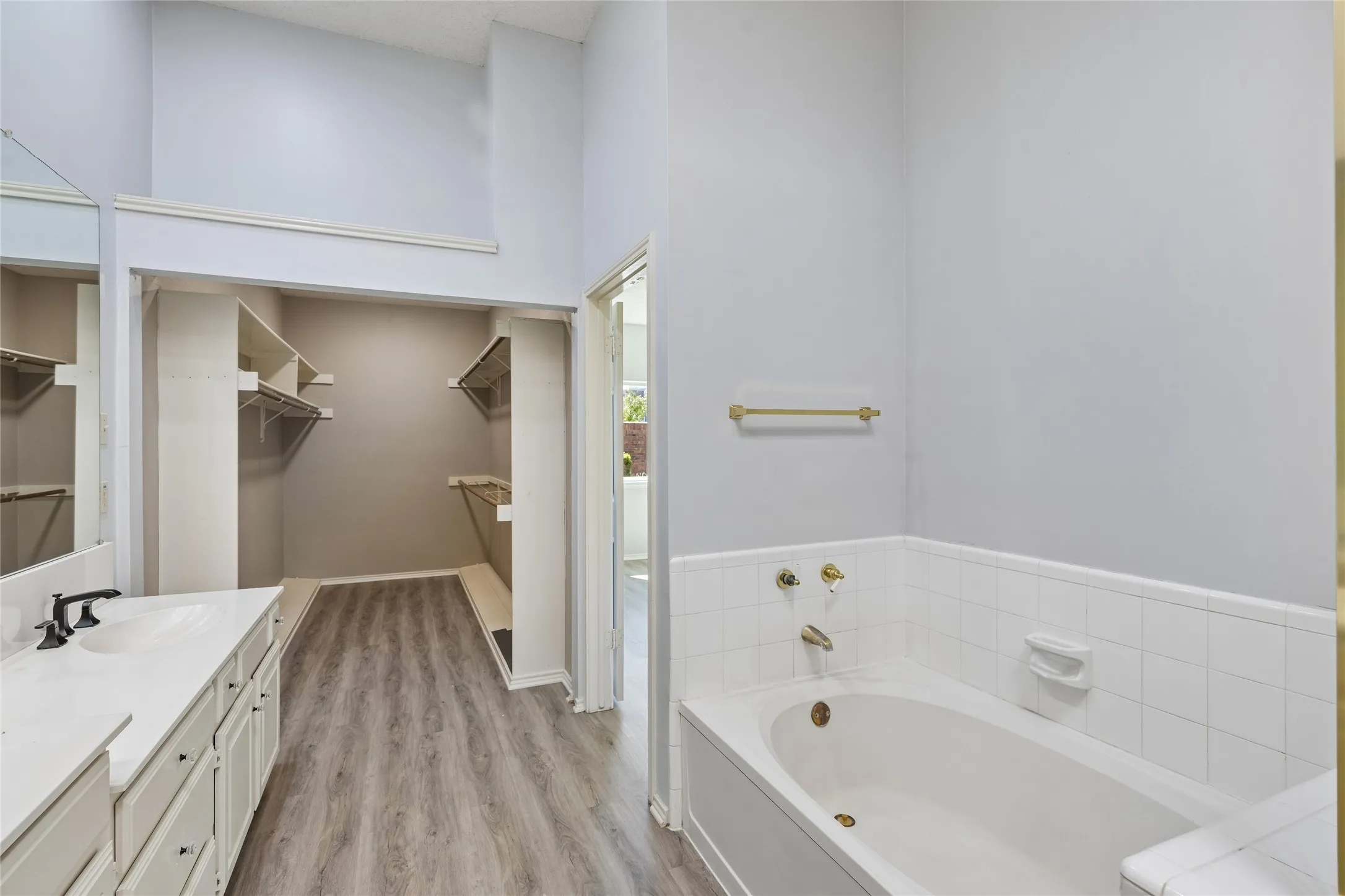 The primary ensuite bath also with luxury vinyl flooring leads into a large walk-in closet.