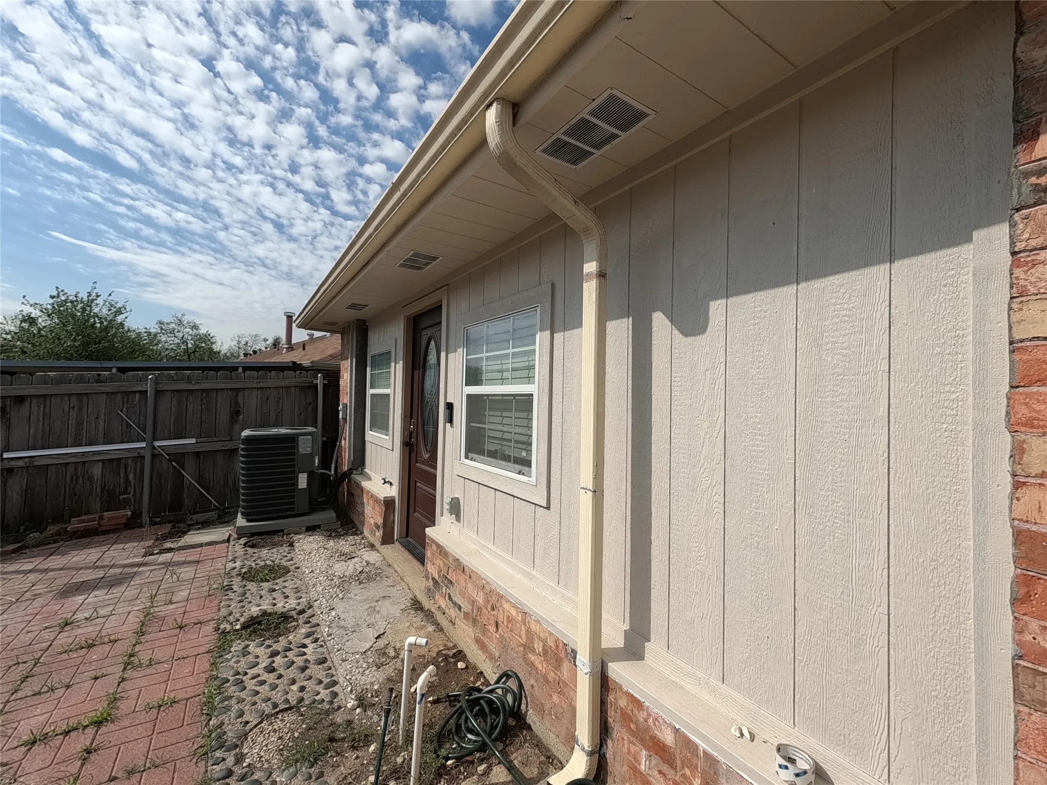Exterior siding with brick detailing, white window frames, and a dark entry door