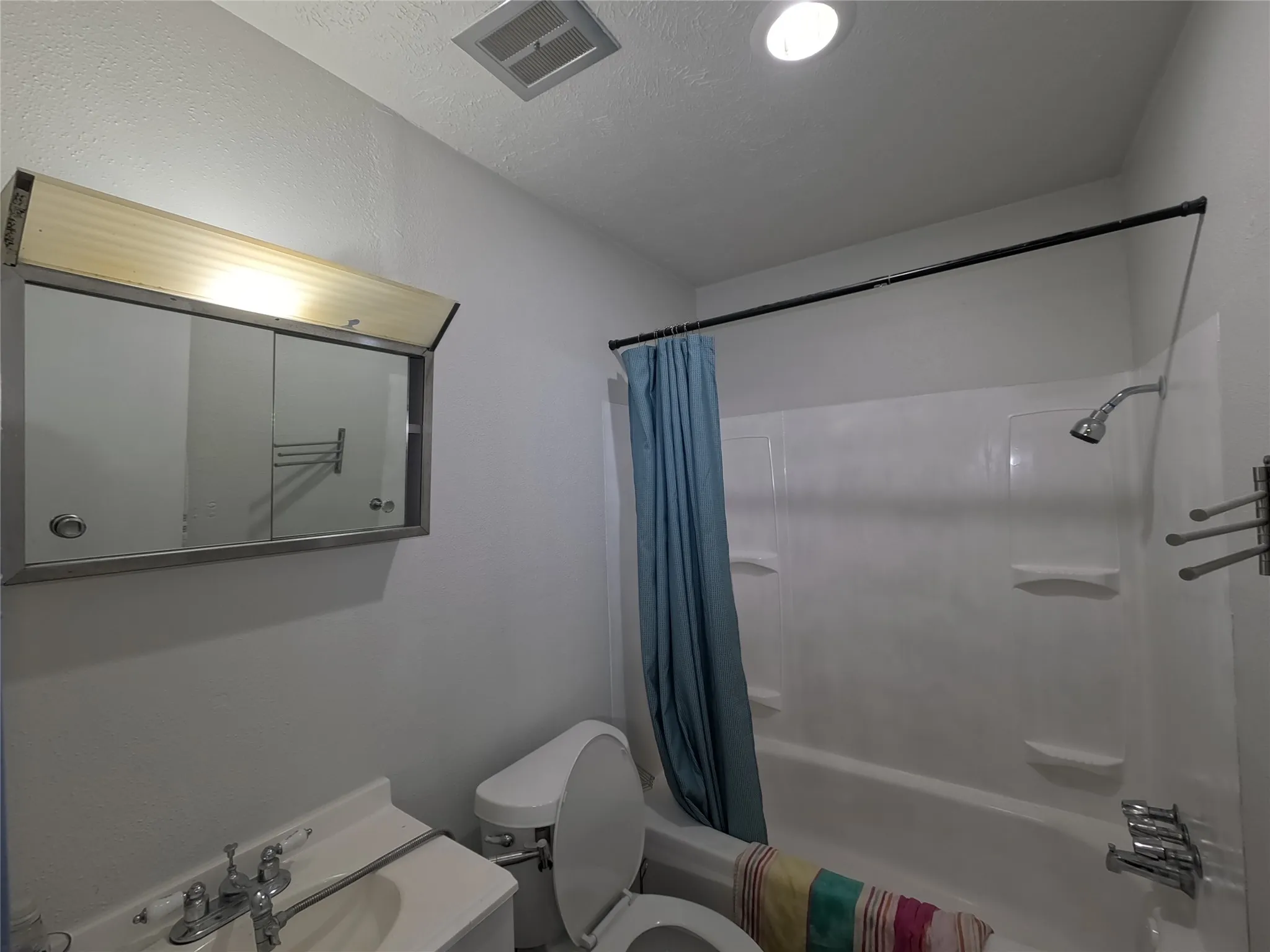 White bathtub with integrated shelving, chrome showerhead, and wall-mounted towel bars