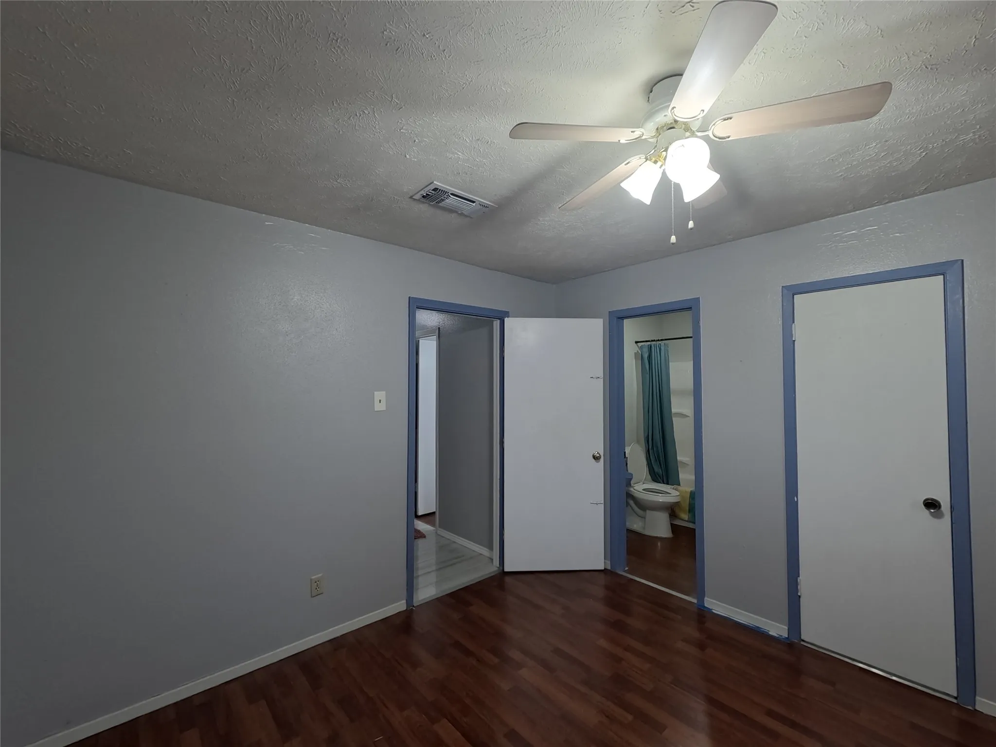 Wood-finish flooring with light gray walls, white doors, and a ceiling fan with light fixture