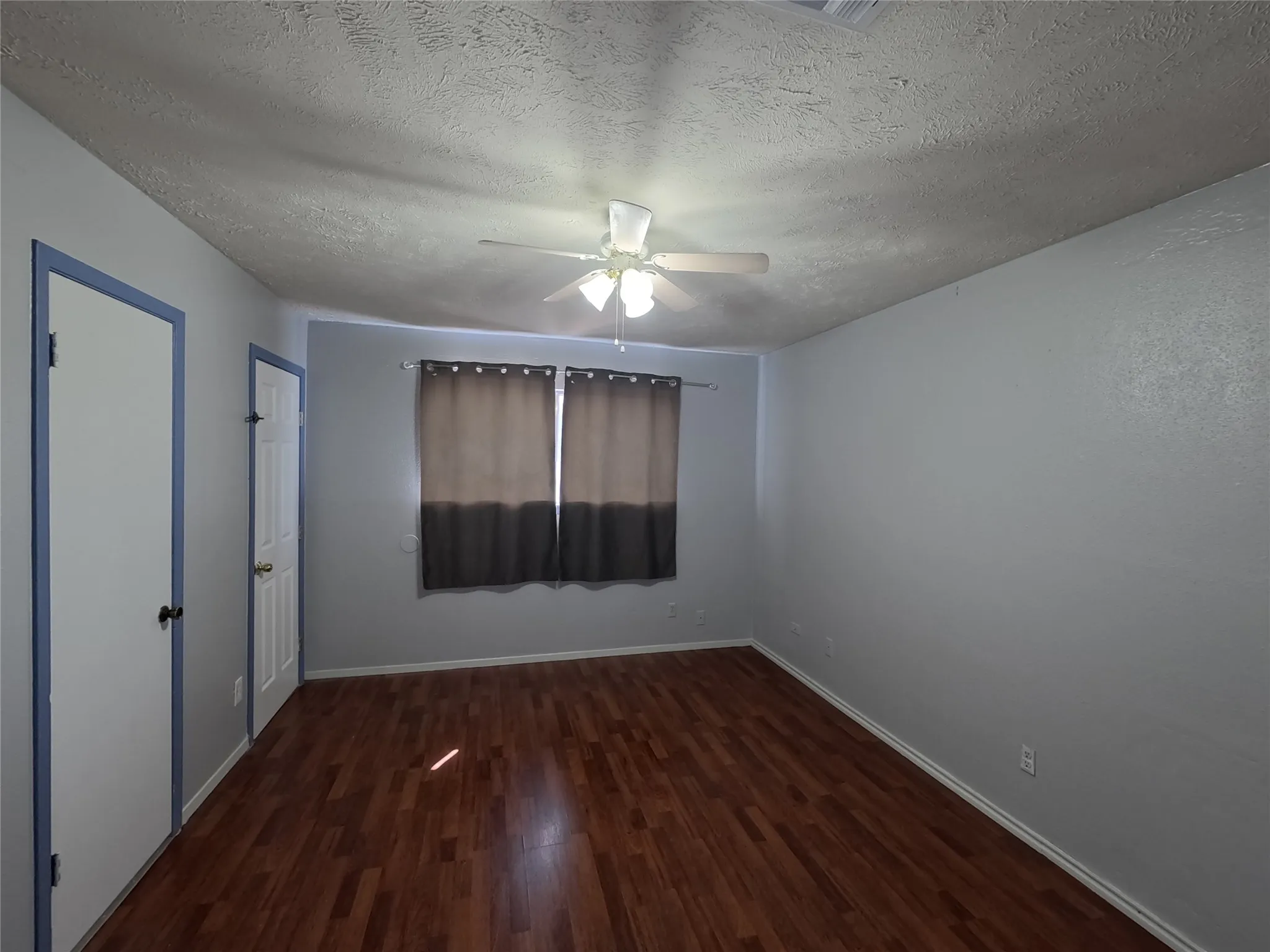 Wood-finish flooring throughout, light gray wall finishes, and a ceiling fan with integrated lighting