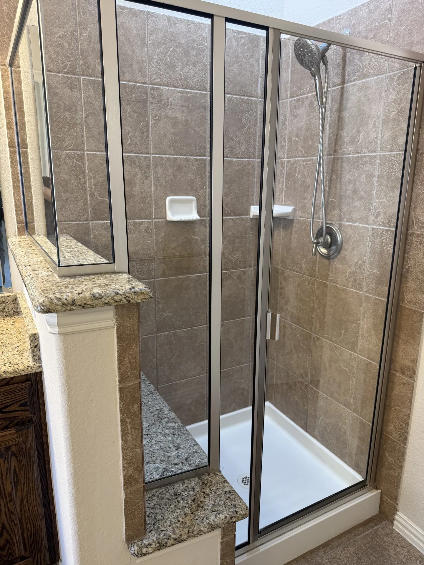 Glass-enclosed shower with a white acrylic pan and tile surround