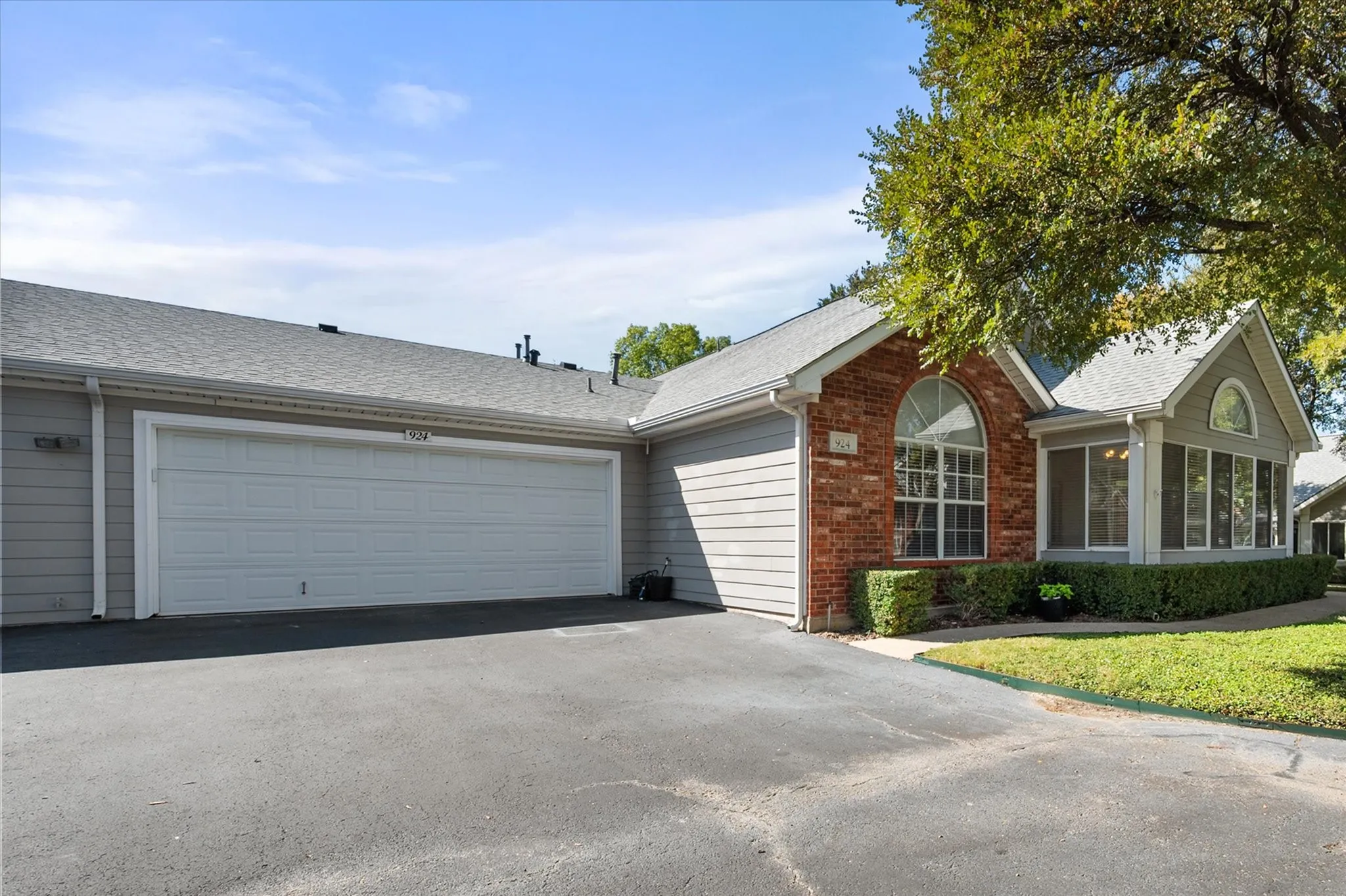 Siding exterior with brick accents, an arched window, and an attached two-car garage
