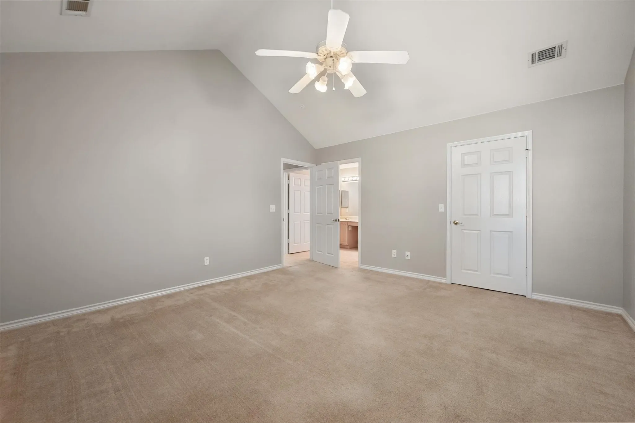 Vaulted ceiling with a ceiling fan, light-toned carpeting, and a six-panel door
