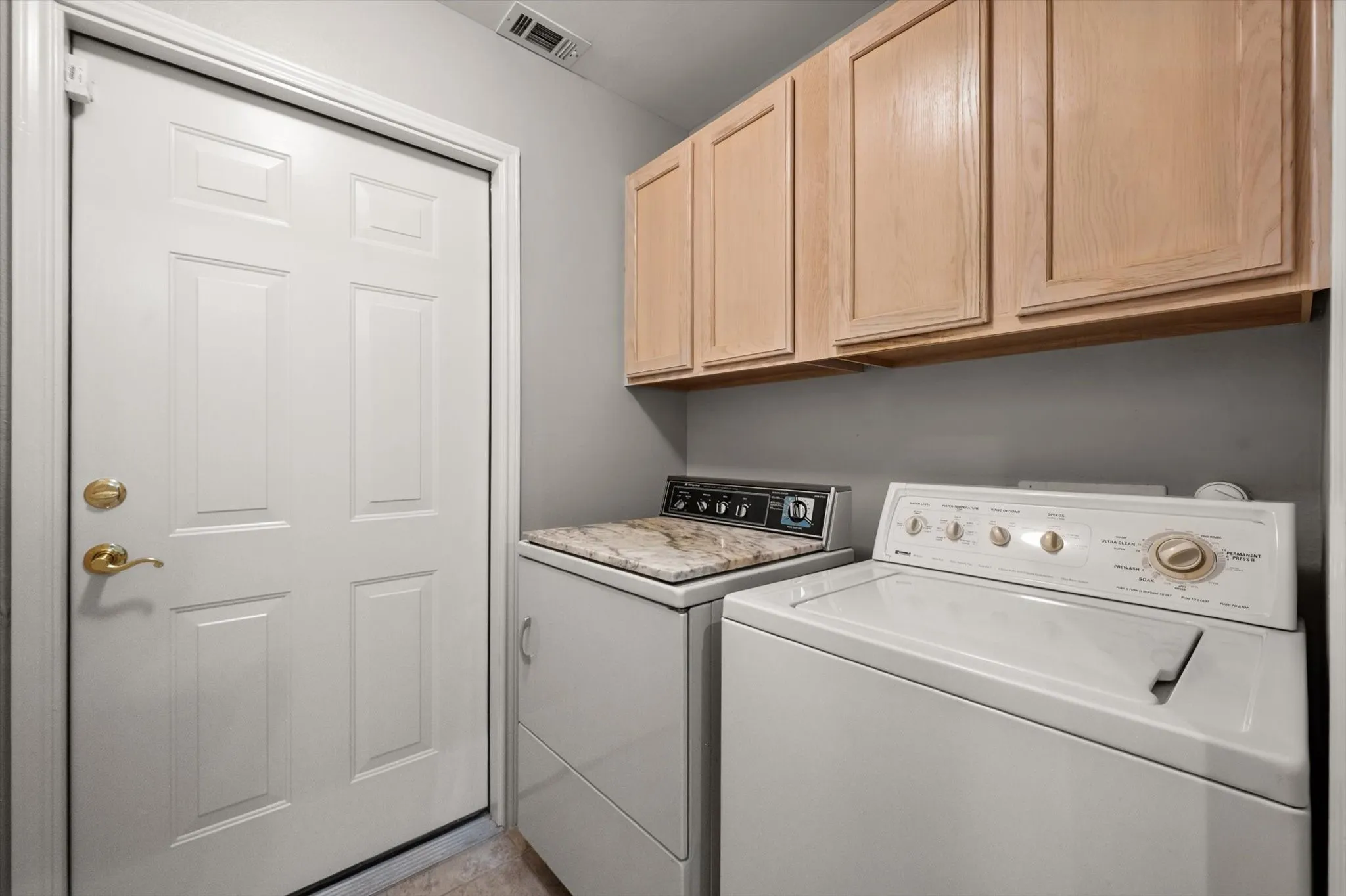 Overhead cabinetry, neutral wall color, and a paneled door with brass-finish hardware