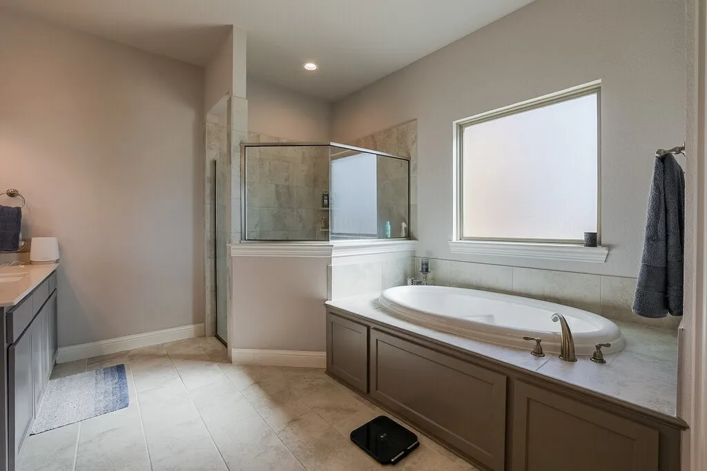 Recessed lighting, tile flooring, built-in soaking tub with deck-mounted faucet, and glass-enclosed shower