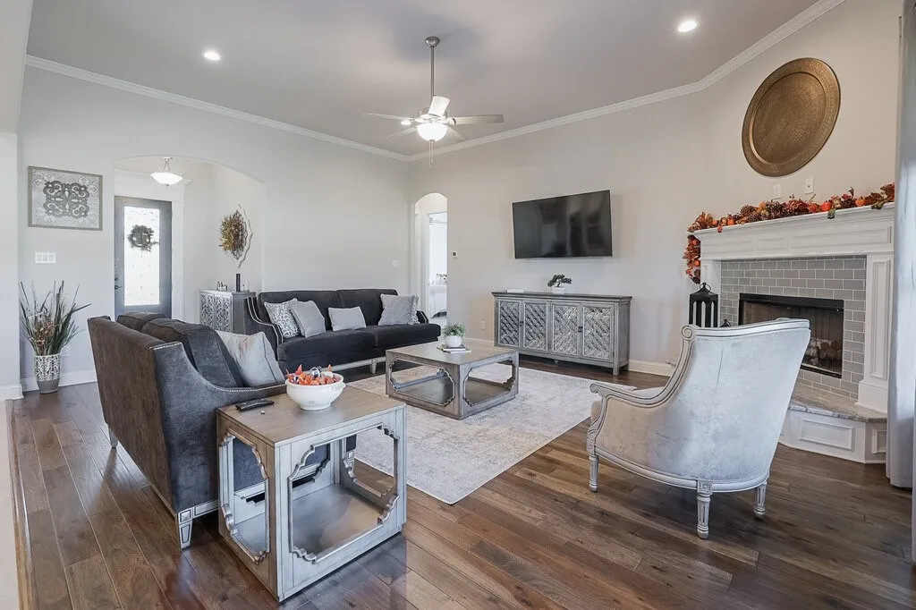 Spacious living area featuring wood-finish flooring, a vaulted ceiling, a built-in fireplace with a tiled surround, and recessed lighting