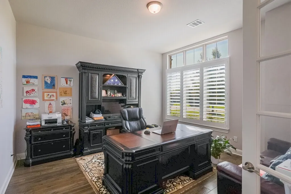 Wood-finish flooring, high ceilings, transom windows, and white plantation shutters