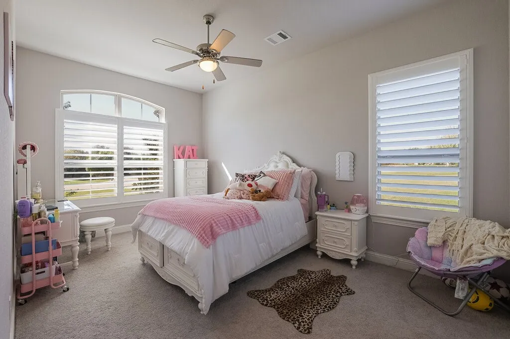 Recessed lighting, ceiling fan with integrated light, arched window, plantation shutters, and light-colored carpeting