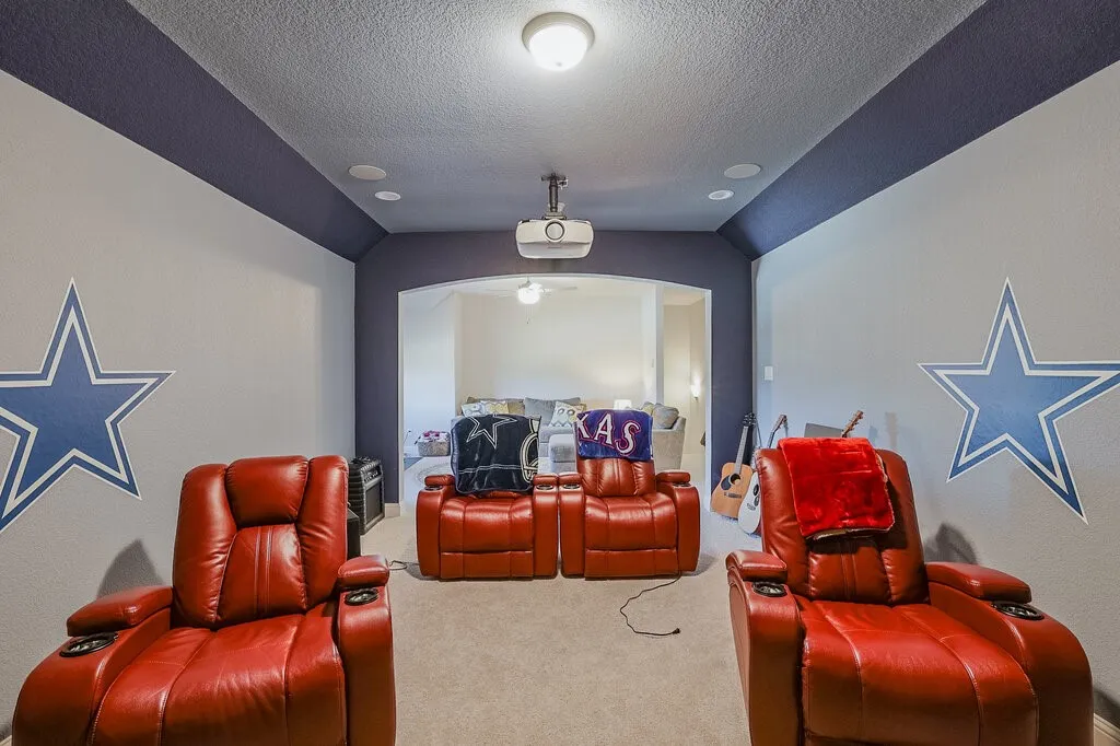 Recessed ceiling lighting, projector, built-in ceiling speakers, arched entryway, and carpeted flooring