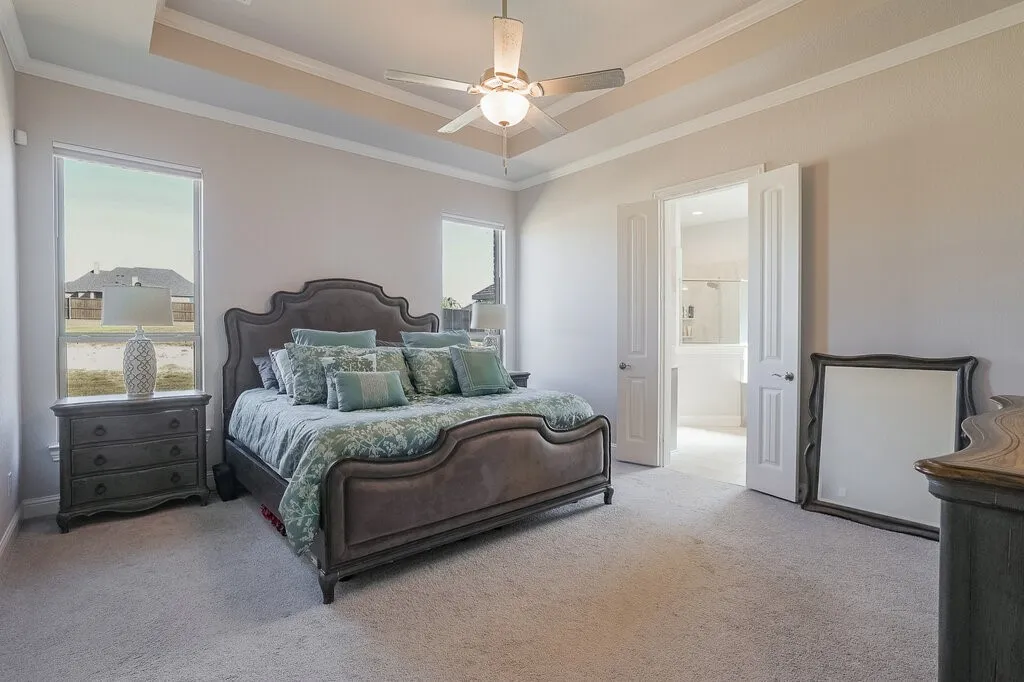 Tray ceiling with crown molding, ceiling fan with integrated lighting, recessed windows with trim, and a double-door entry