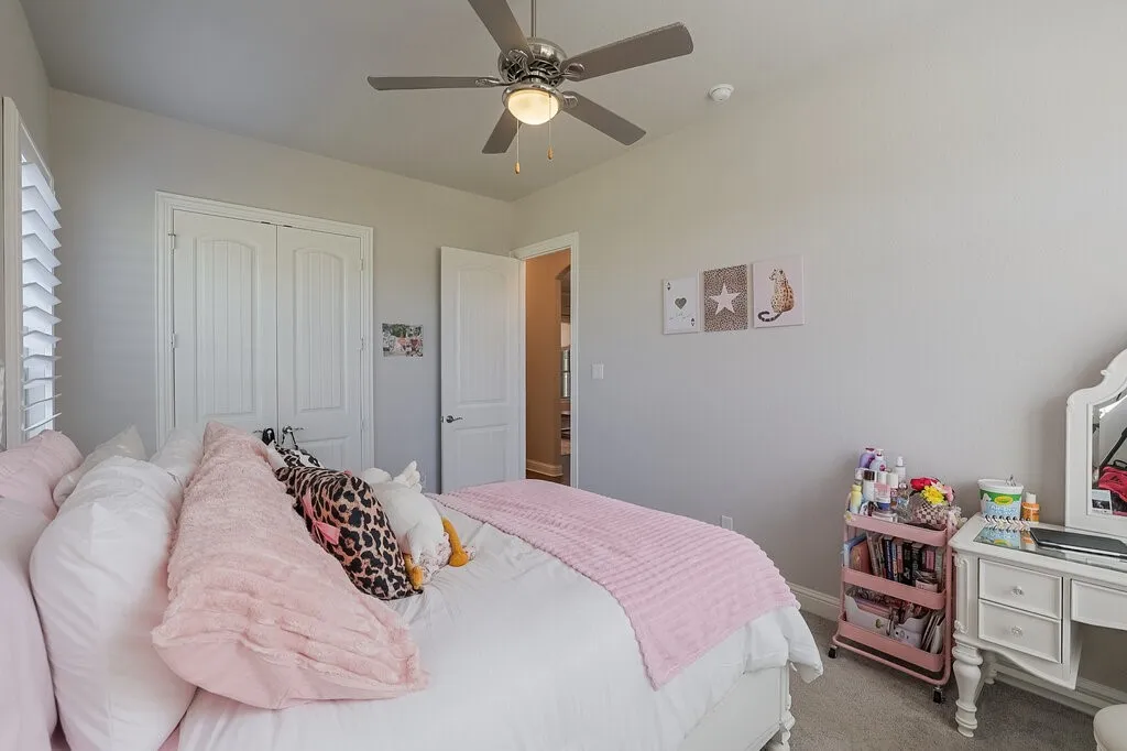 Ceiling fan with integrated lighting, window with plantation shutters, double closet doors, and a paneled interior door