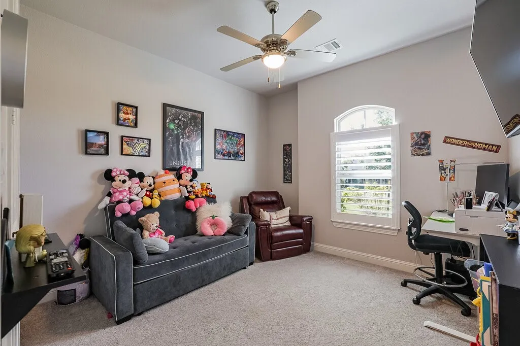 Arched window with plantation shutters, ceiling fan with integrated lighting, and carpeted flooring