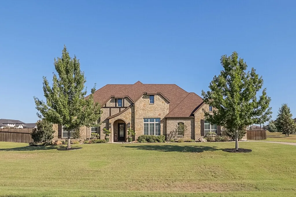 Stone exterior with a shingle roof and arched entry