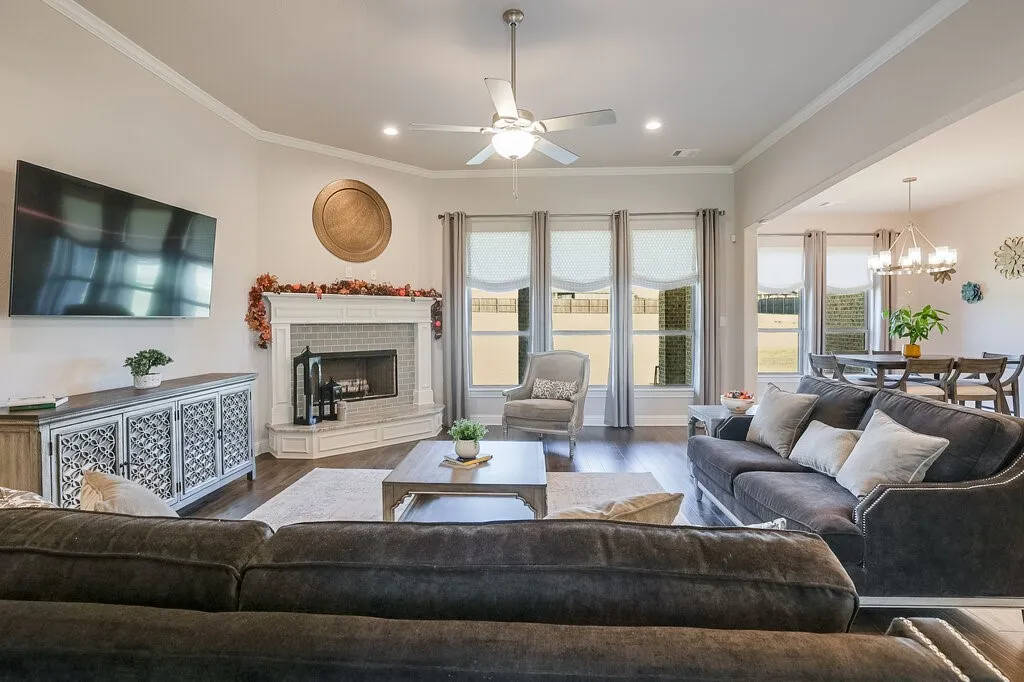 Living space featuring dark wood-finish flooring, a corner fireplace with white brick surround, recessed lighting, and a ceiling fan