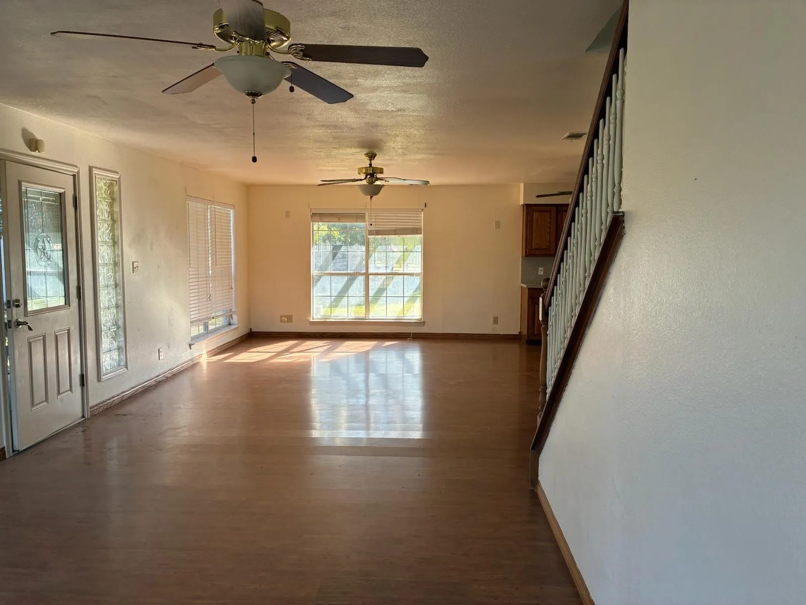 Spare room featuring wood finished floors, stairway, a textured ceiling, and a ceiling fan