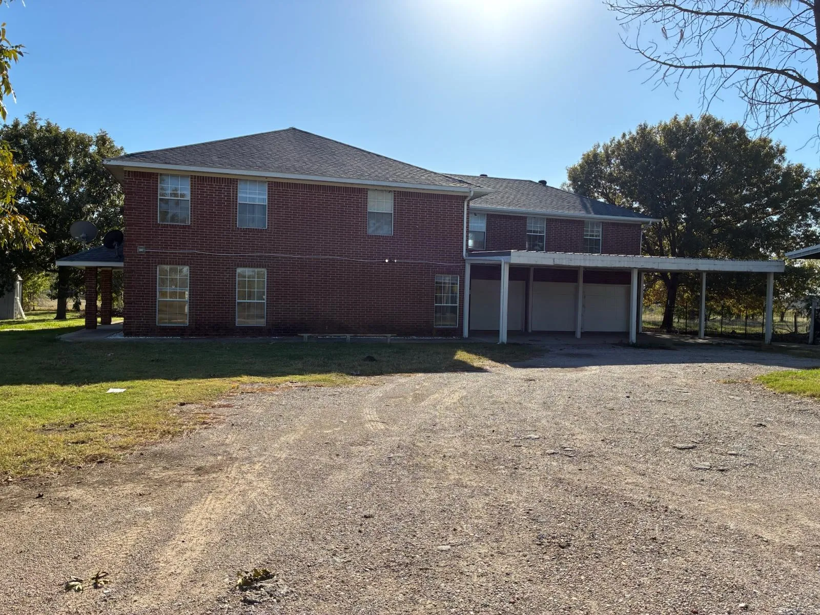 View of front facade featuring dirt driveway, brick siding, and a garage