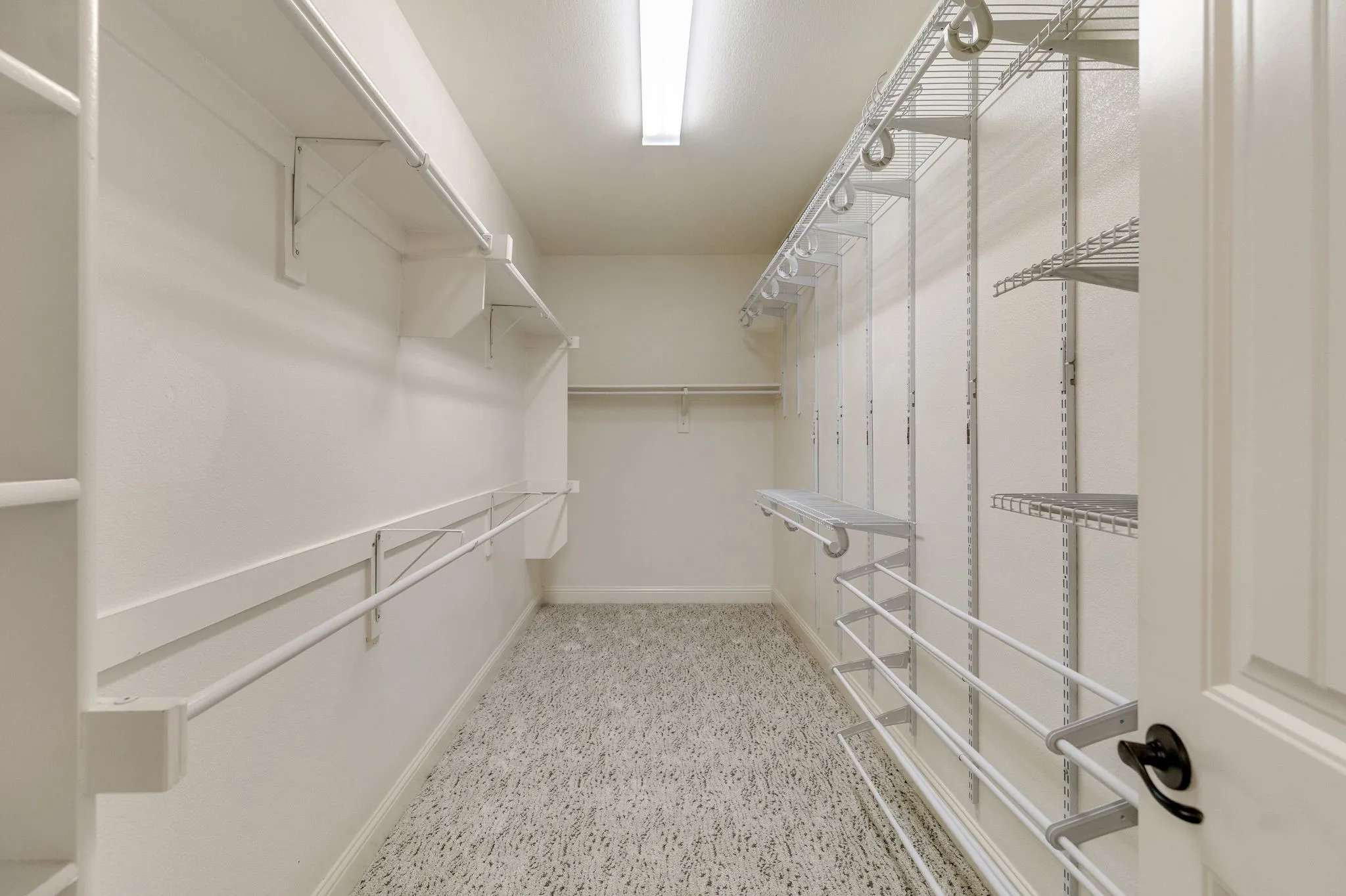 Spacious Primary walk-in closet featuring built-in shelving, hanging rods, and adjustable wire rack storage system