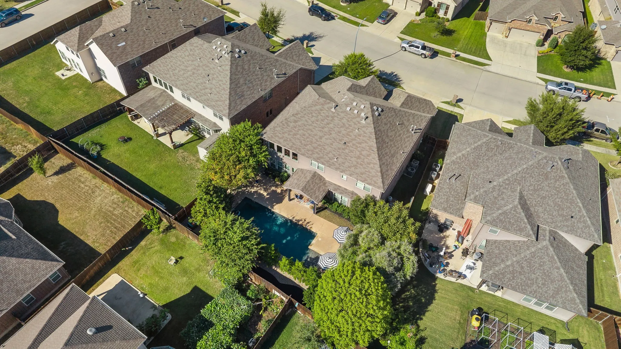 Expansive backyard featuring a swimming pool, paved patio, and mature trees